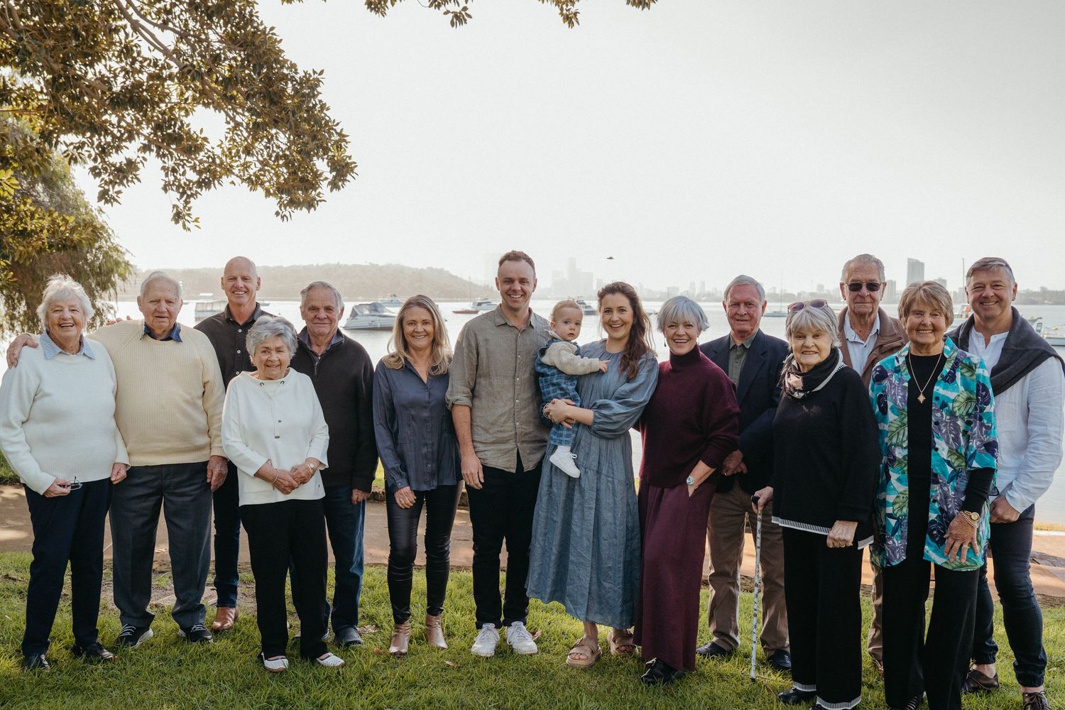 A group of people standing together outdoors on a hillside with trees and mountains in the background.