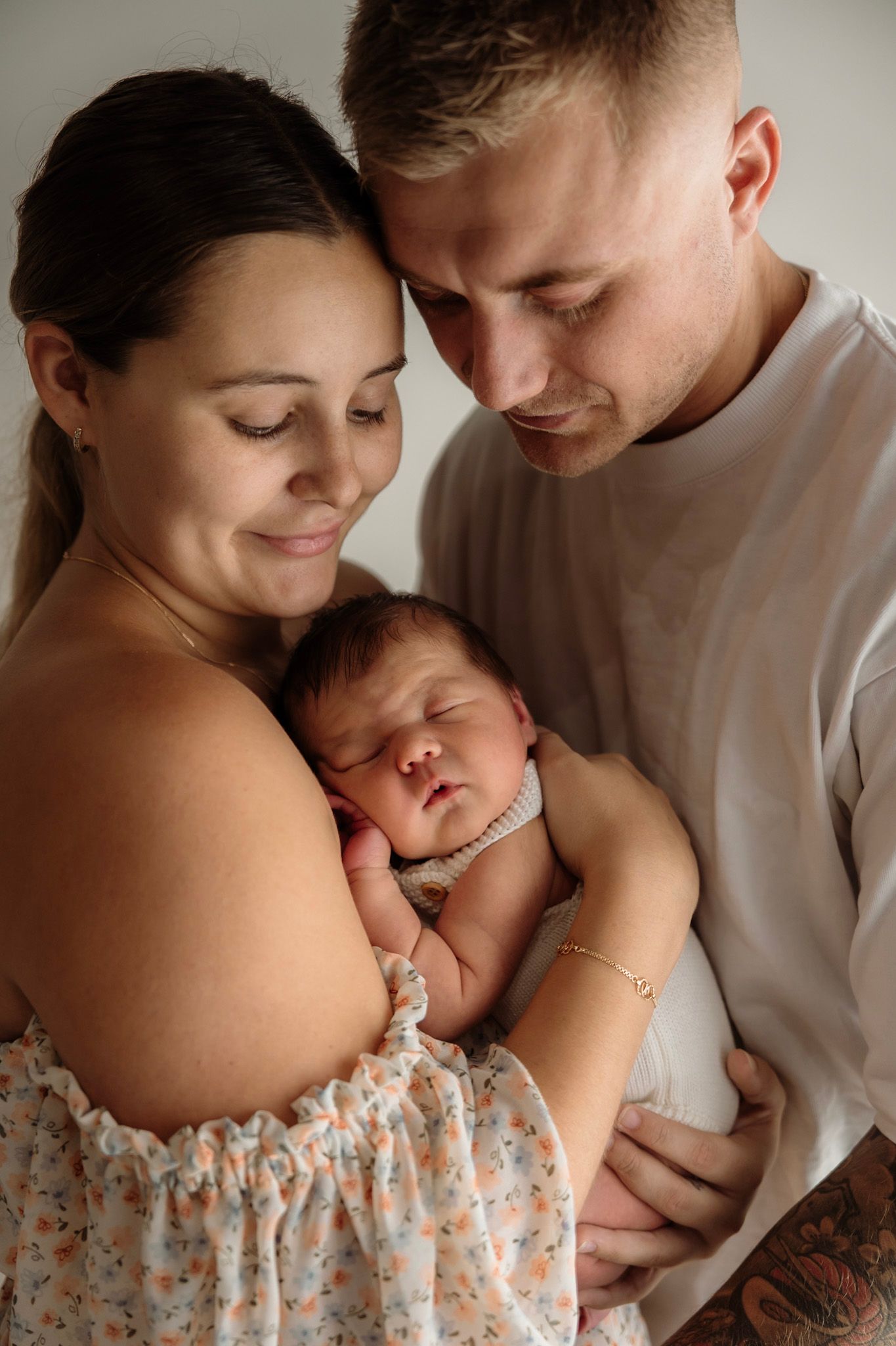 Couple shares intimate moment with their sleeping newborn baby in tender family portrait.