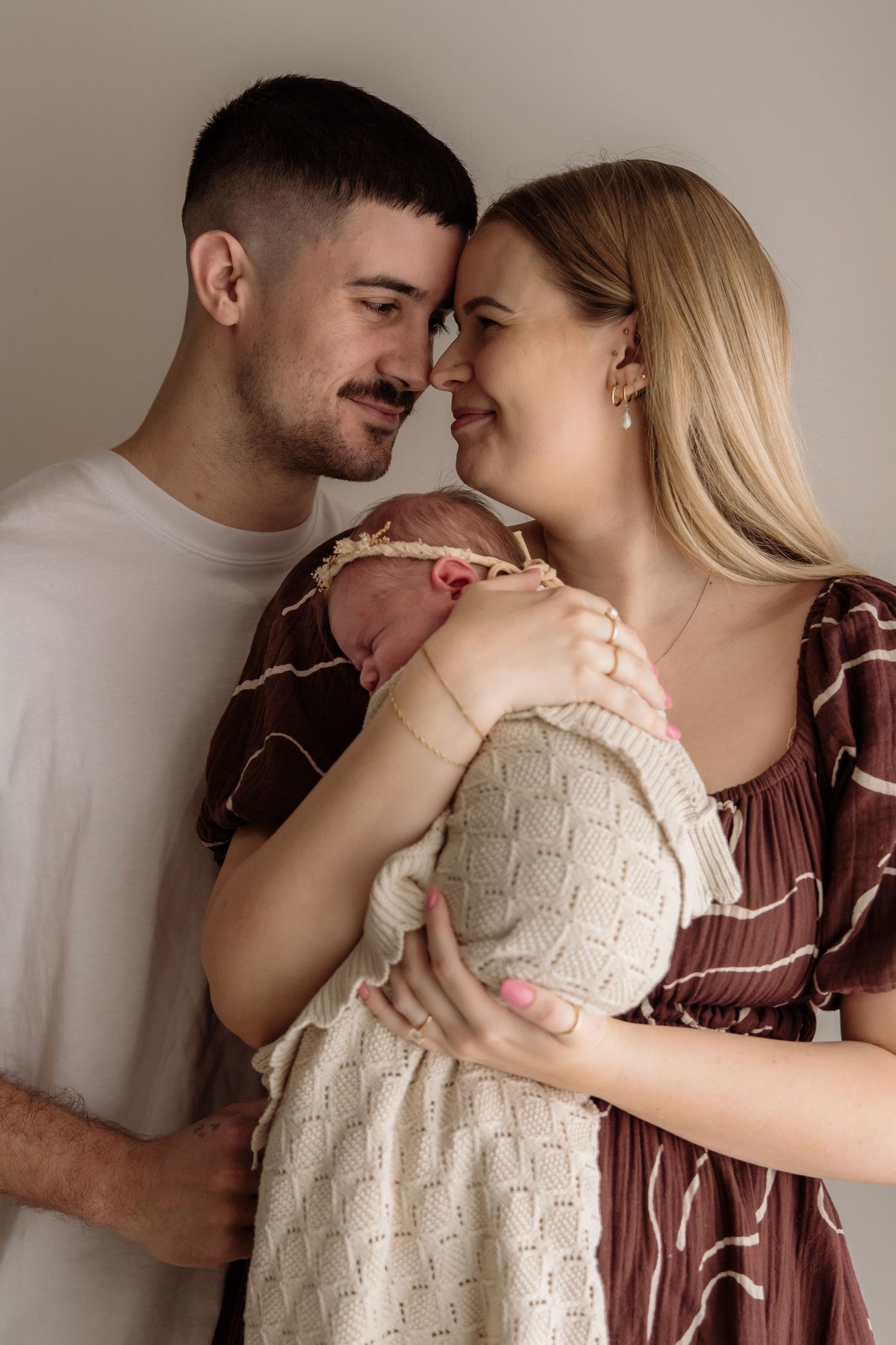 A series of intimate moments between a couple in casual clothing against a neutral wall.