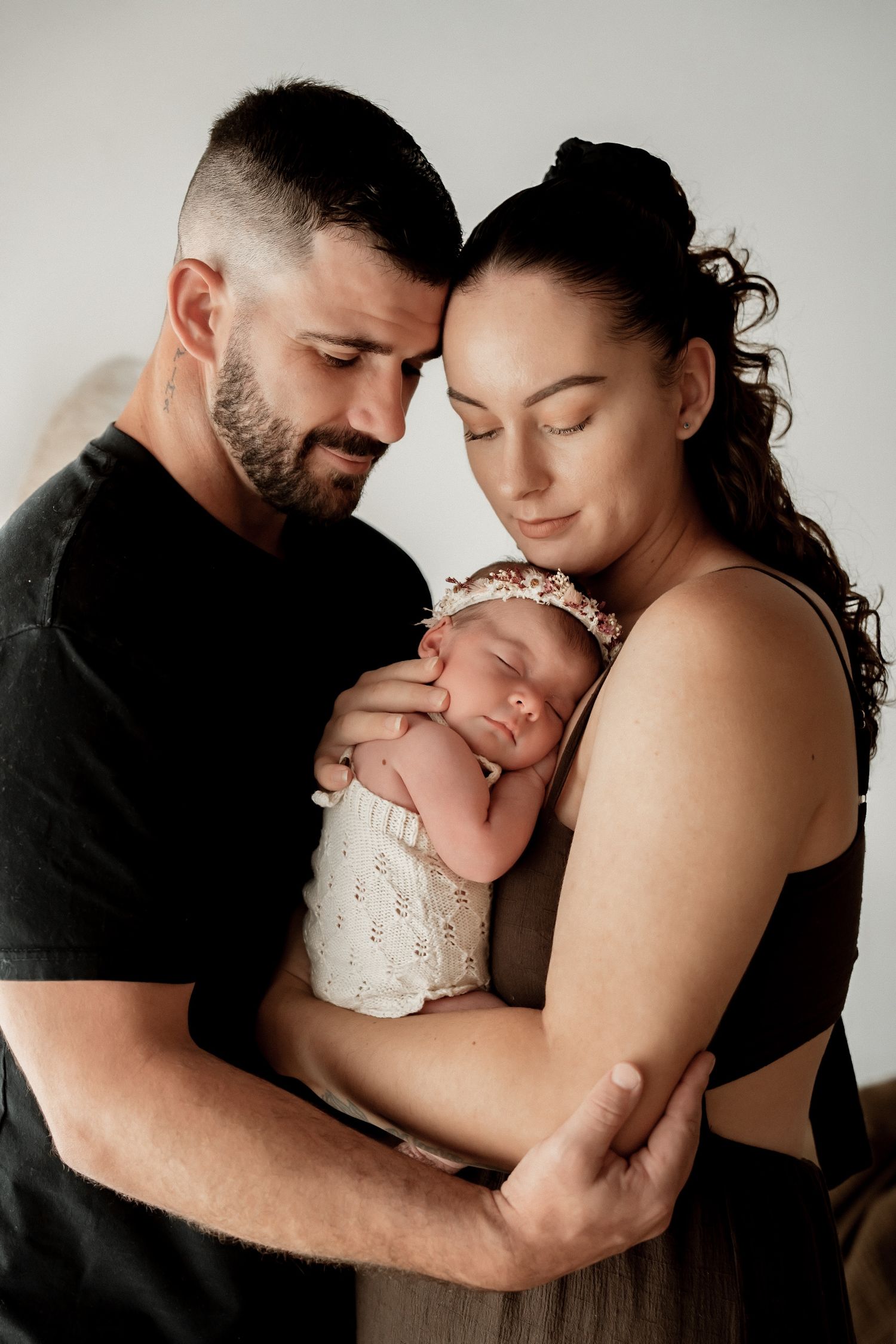 A series of intimate black and white family portraits showing tender moments between parents and their newborn baby.