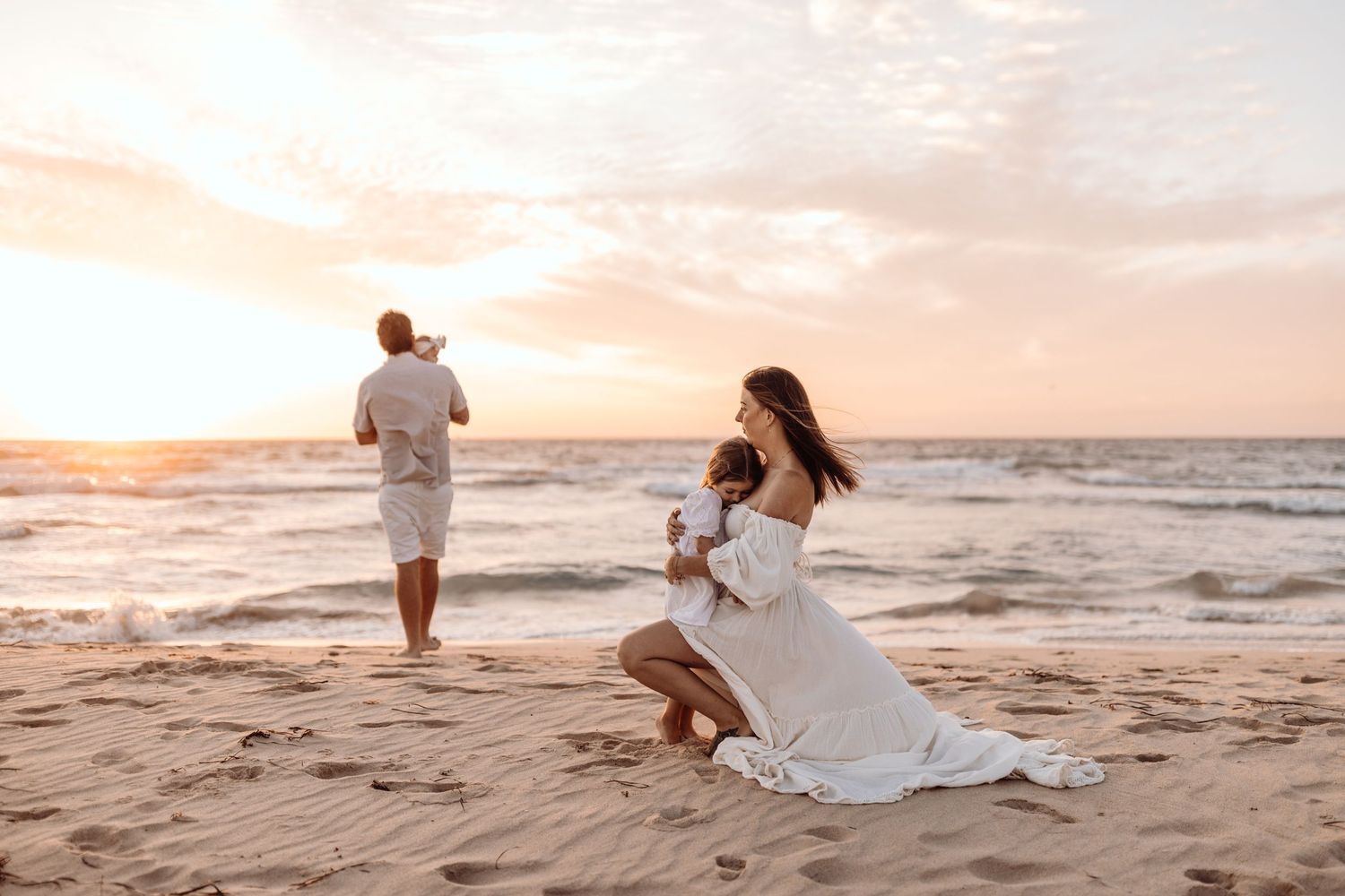 Ethereal beach scene with woman in flowing white dress at sunset.