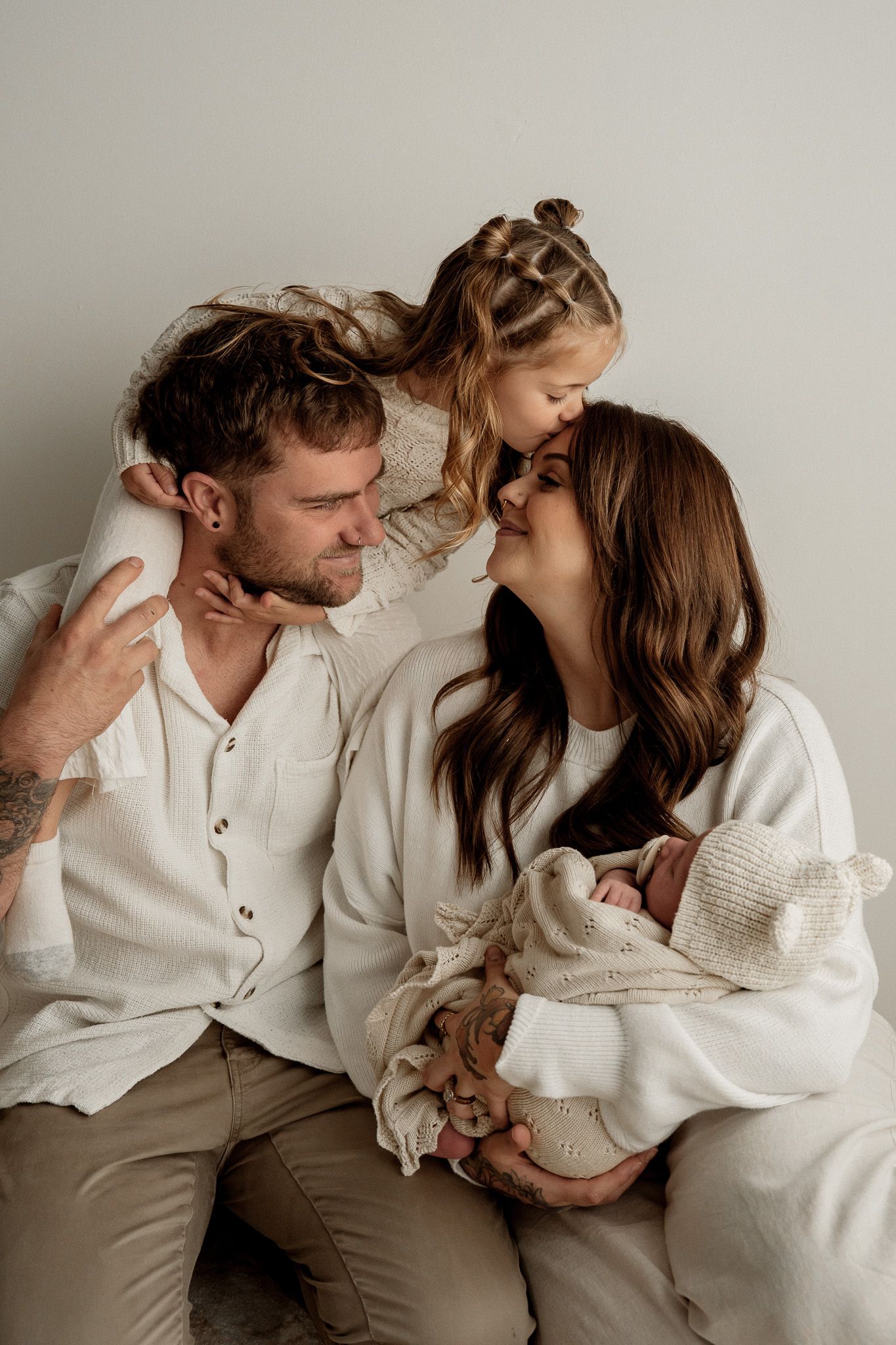A couple in cozy white and beige outfits share intimate moments together in a progression of romantic poses.
