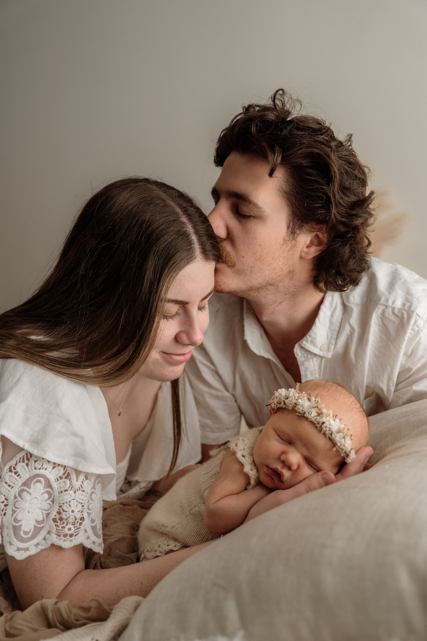 Romantic sequence of couple sharing tender moments while lying together in bed with soft neutral tones and lace details.