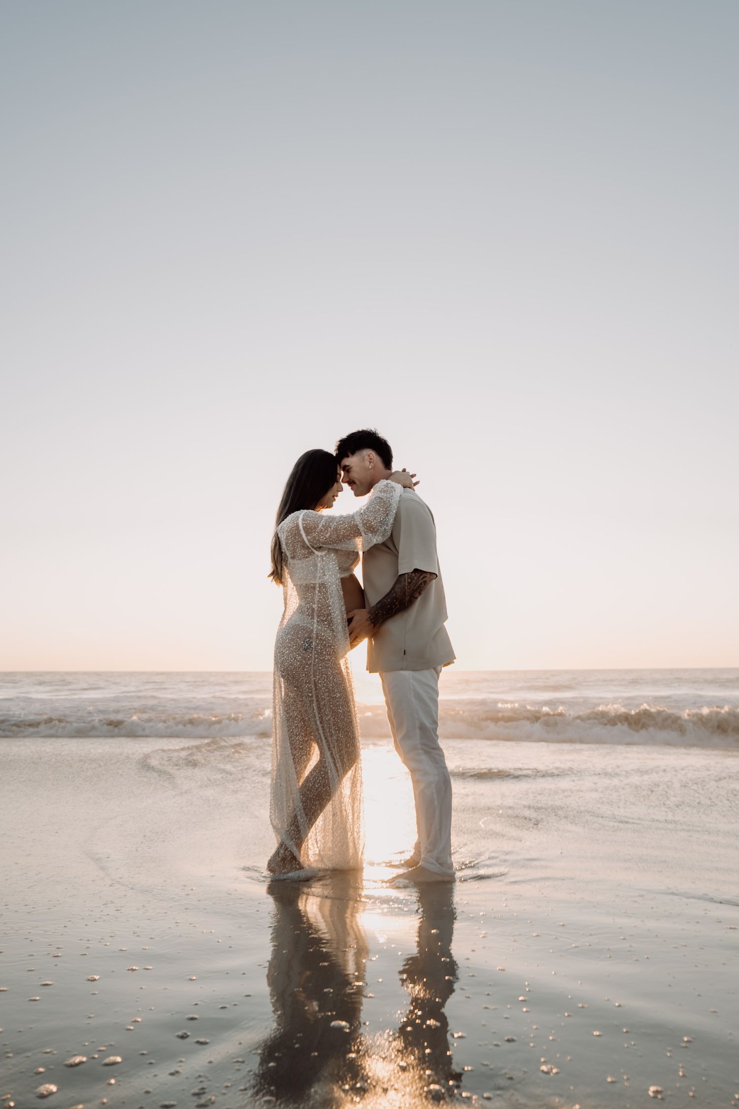 A couple embraces on a misty beach at sunset in a romantic five-photo series showing their silhouettes against golden light.