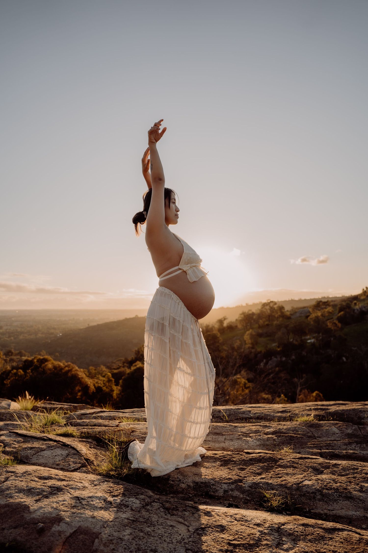 A series of artistic maternity photos showing a woman in a white dress posing on a rocky overlook at sunset.