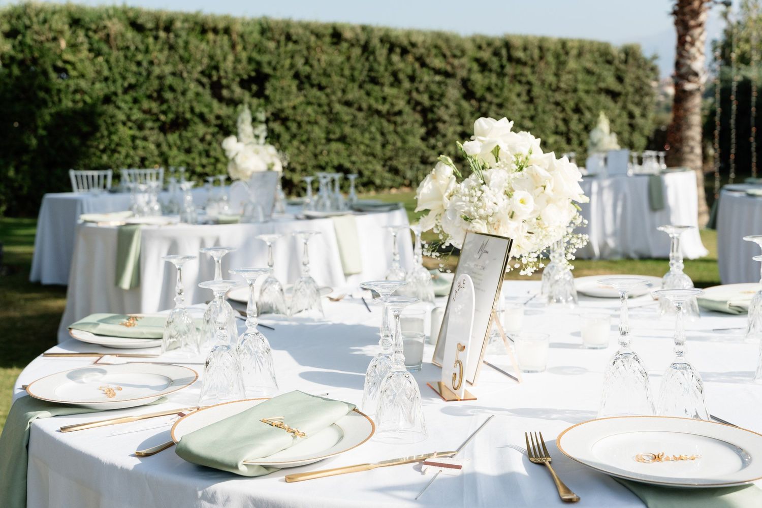 Elegant white table settings with floral centerpieces at an outdoor wedding reception.