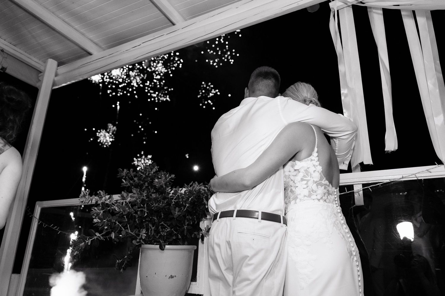 A couple shares an intimate dance moment on a porch decorated with twinkling lights at night.