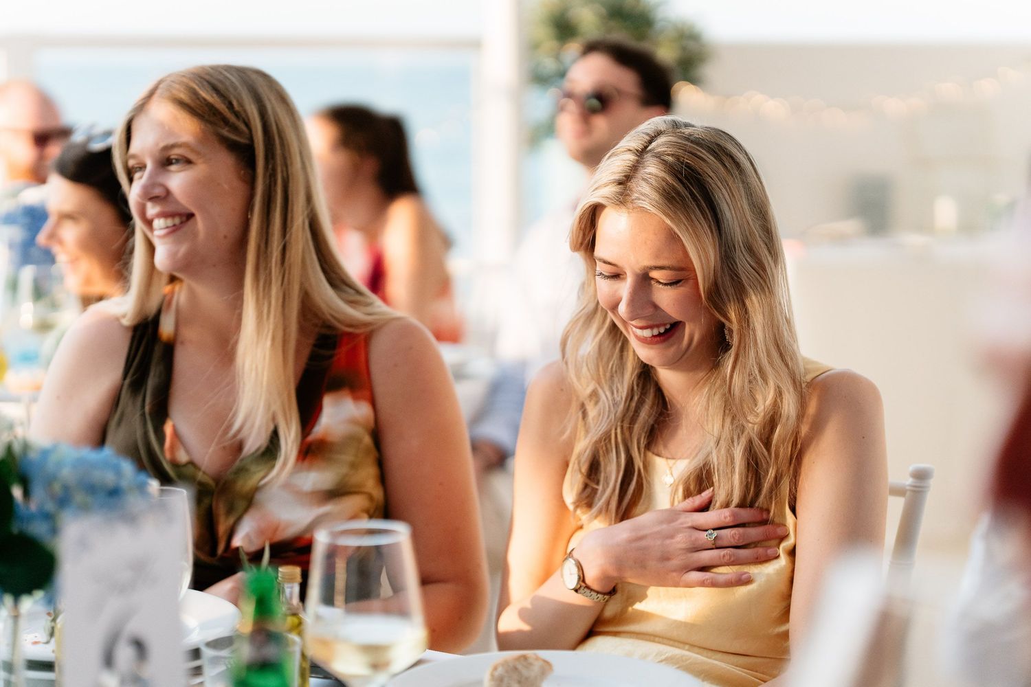 A group of friends laughing together while enjoying drinks and conversation at a social gathering outdoors.