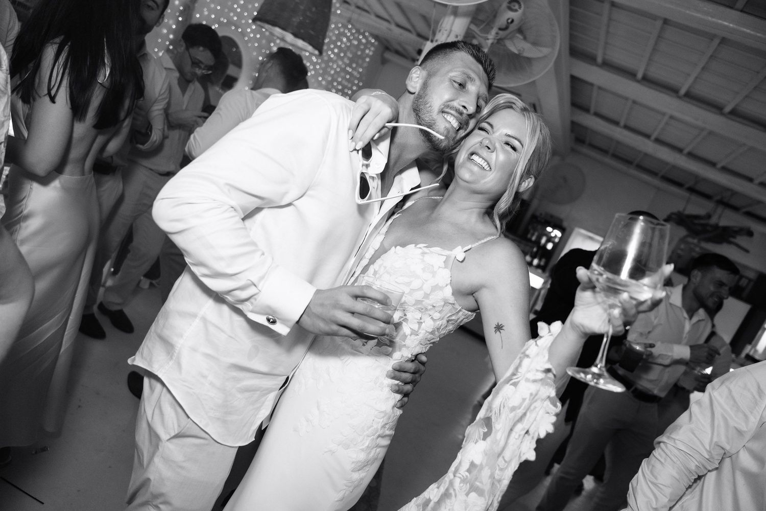 A lively wedding reception dance floor with guests dancing and celebrating in black and white photography.