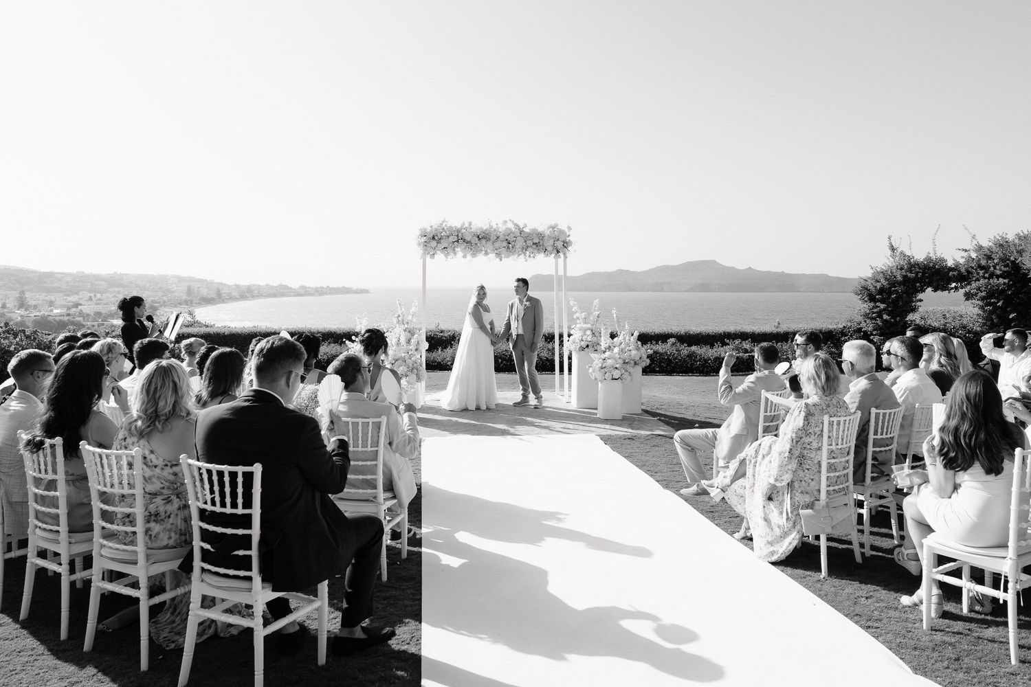Black and white panoramic view of outdoor wedding ceremony seating with mountain landscape in the background.
