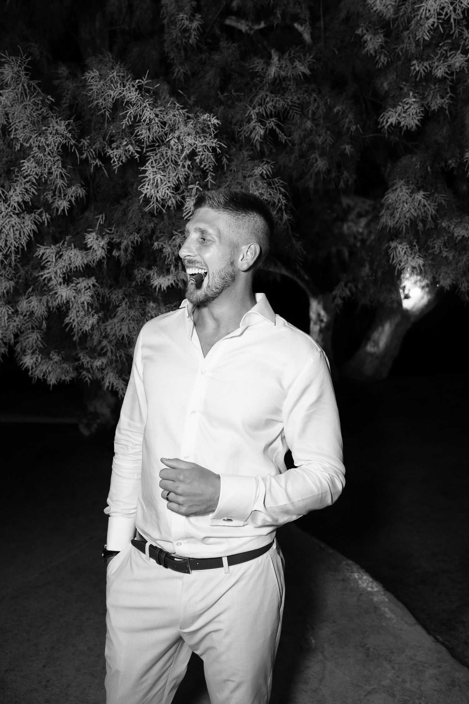 A romantic black and white photo series showing a couple in white clothing embracing and laughing together outdoors.