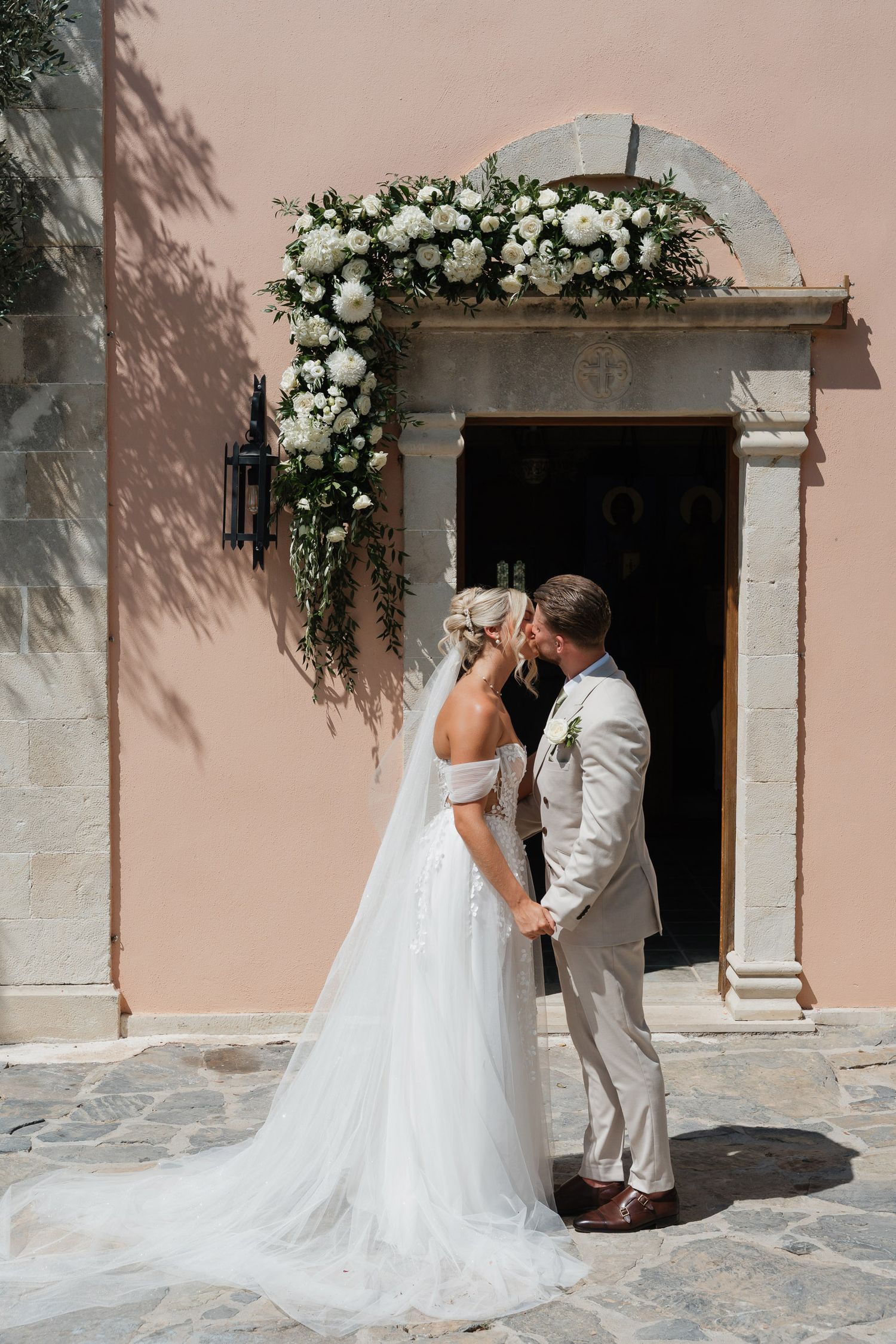 A romantic wedding photoshoot sequence showing a couple in white attire against a pink stucco wall with floral decorations.
