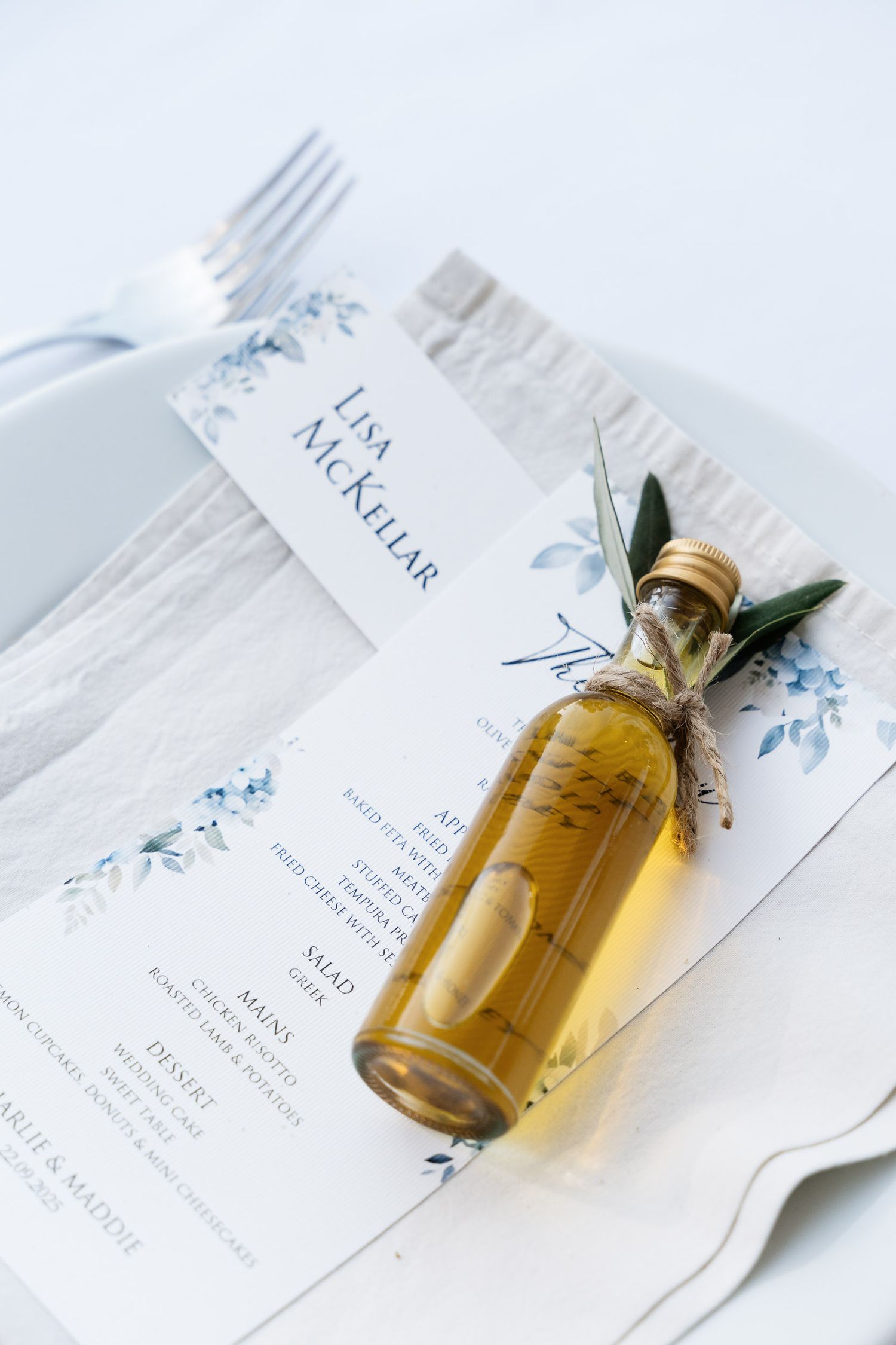 Small glass vials with floral invitation cards in a minimalist white flatlay composition.