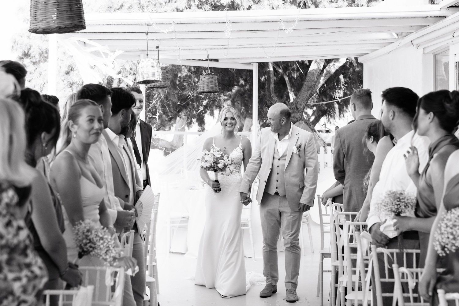 Wedding guests mingle and socialize at an outdoor reception under a white tent.
