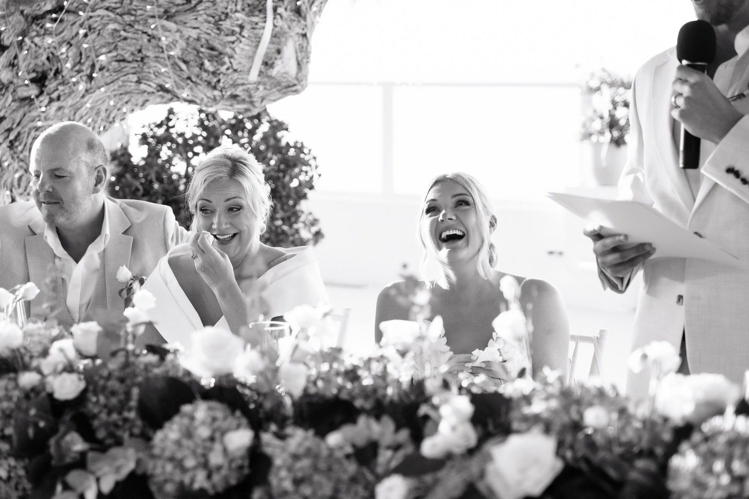 Black and white candid photos of wedding guests laughing and celebrating at an outdoor reception.