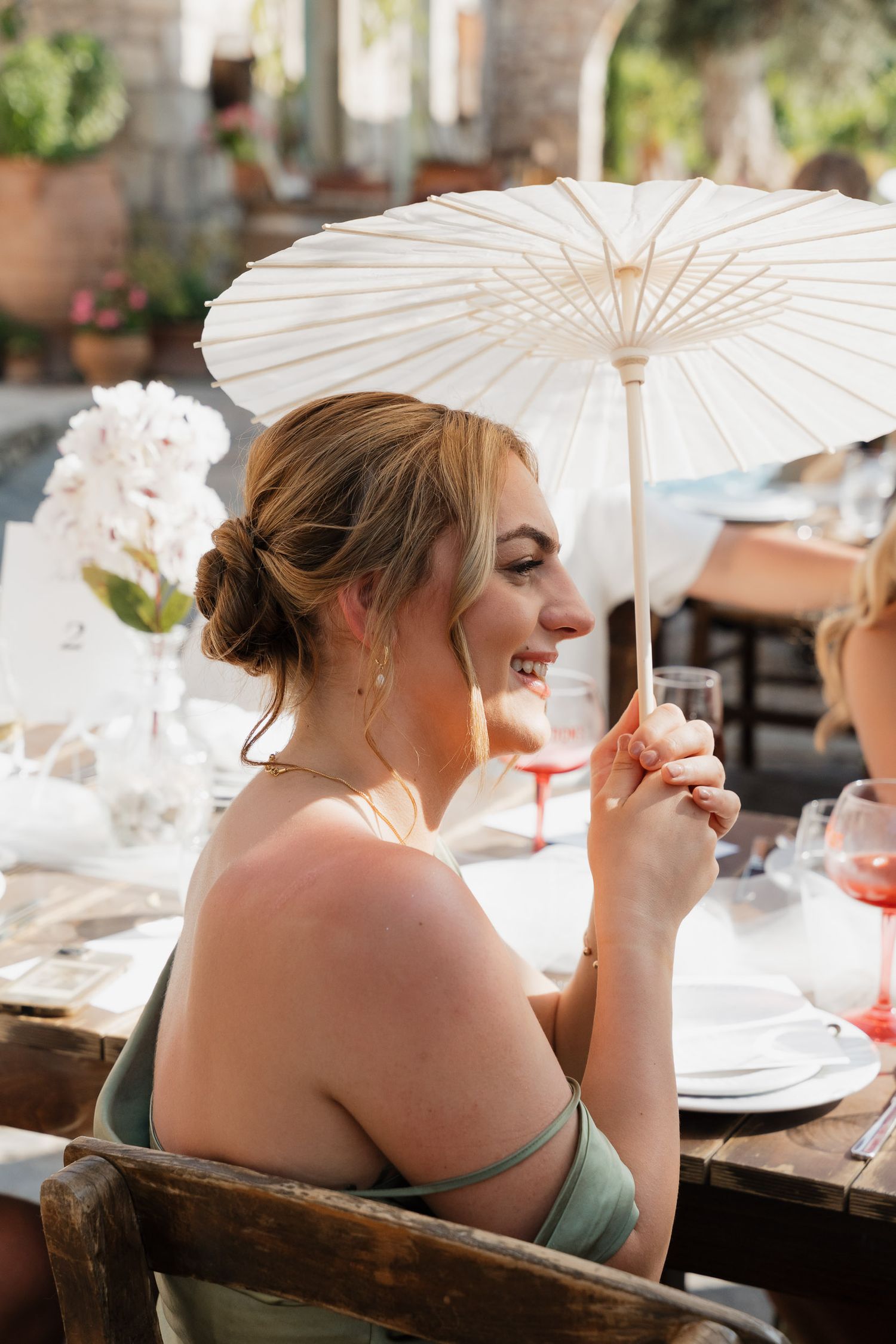 A series of photos showing a person holding a white parasol while seated at an outdoor dining table.