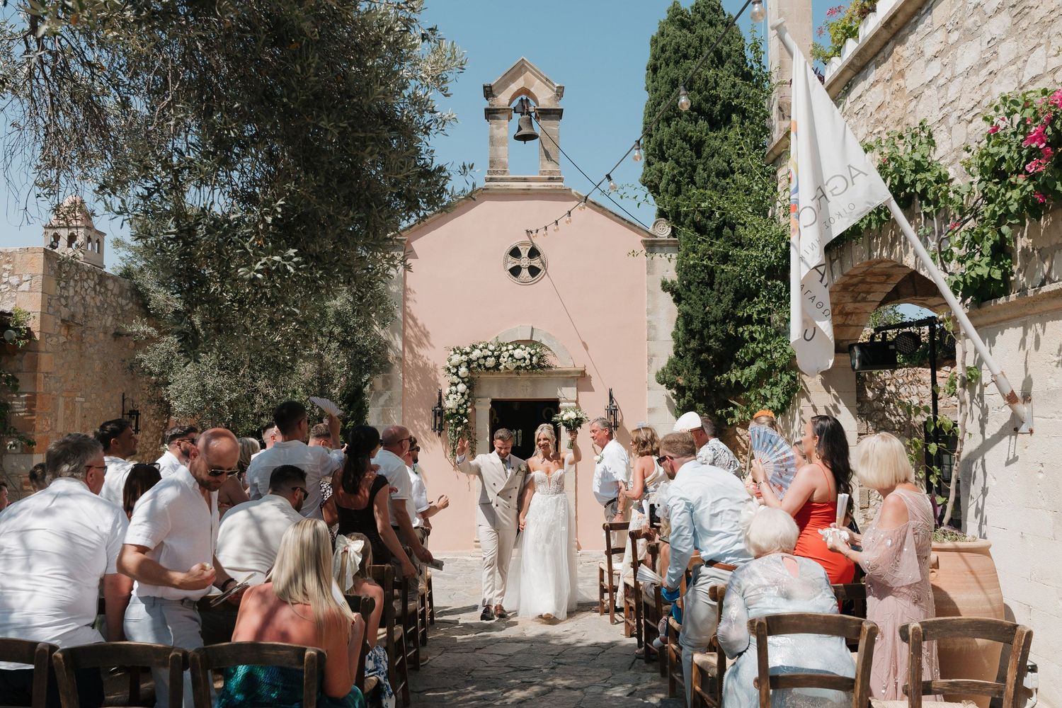 A collection of wedding ceremony photos showing guests and church architecture in an outdoor Mediterranean setting.