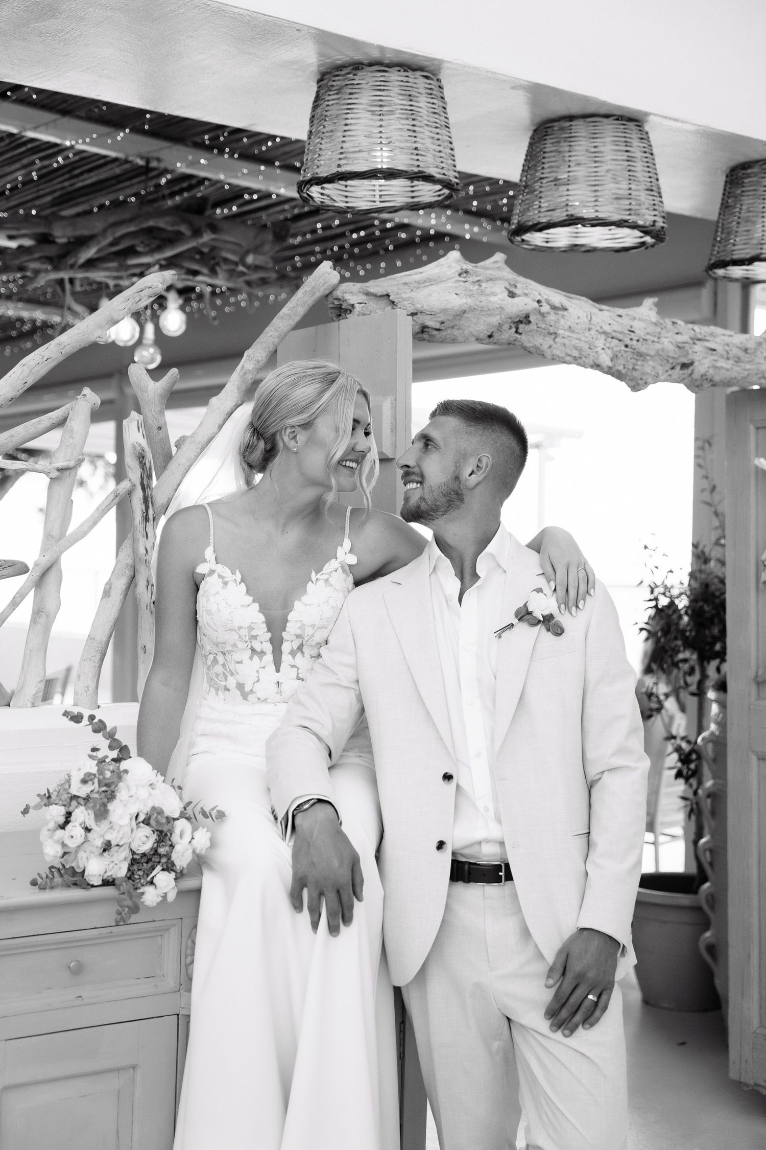Elegant wedding couple in all white sharing an intimate moment under hanging lanterns.