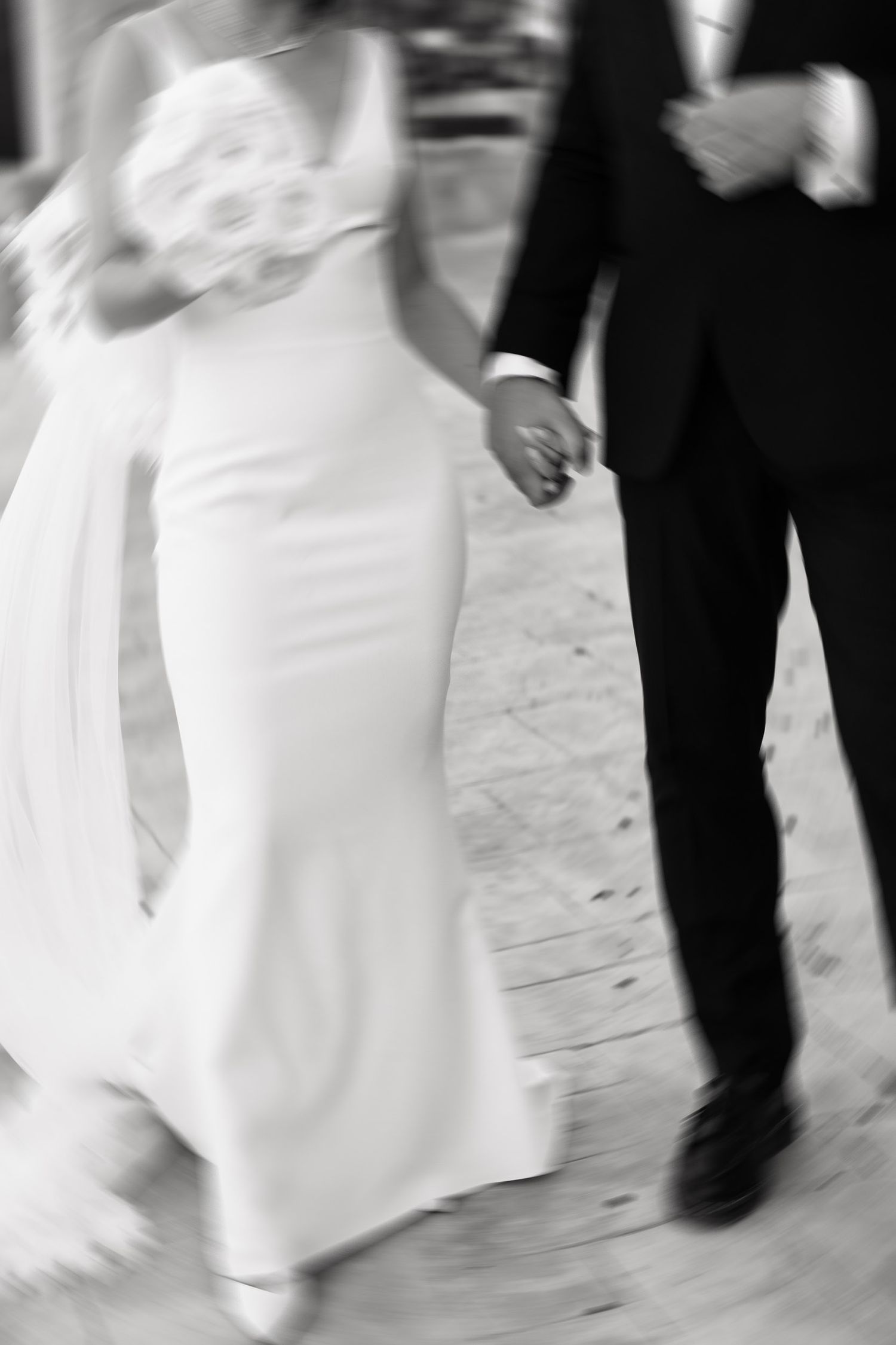 Black and white photo of a bride's white dress flowing in motion as she dances at a wedding reception.