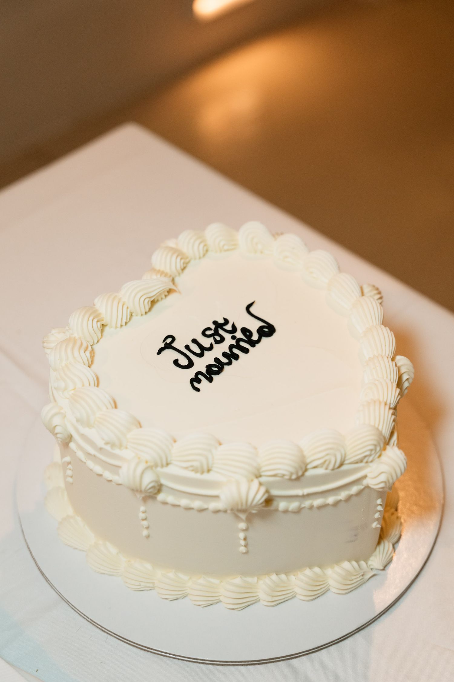 A white frosted cake with decorative piping on a glass plate shown from multiple angles.