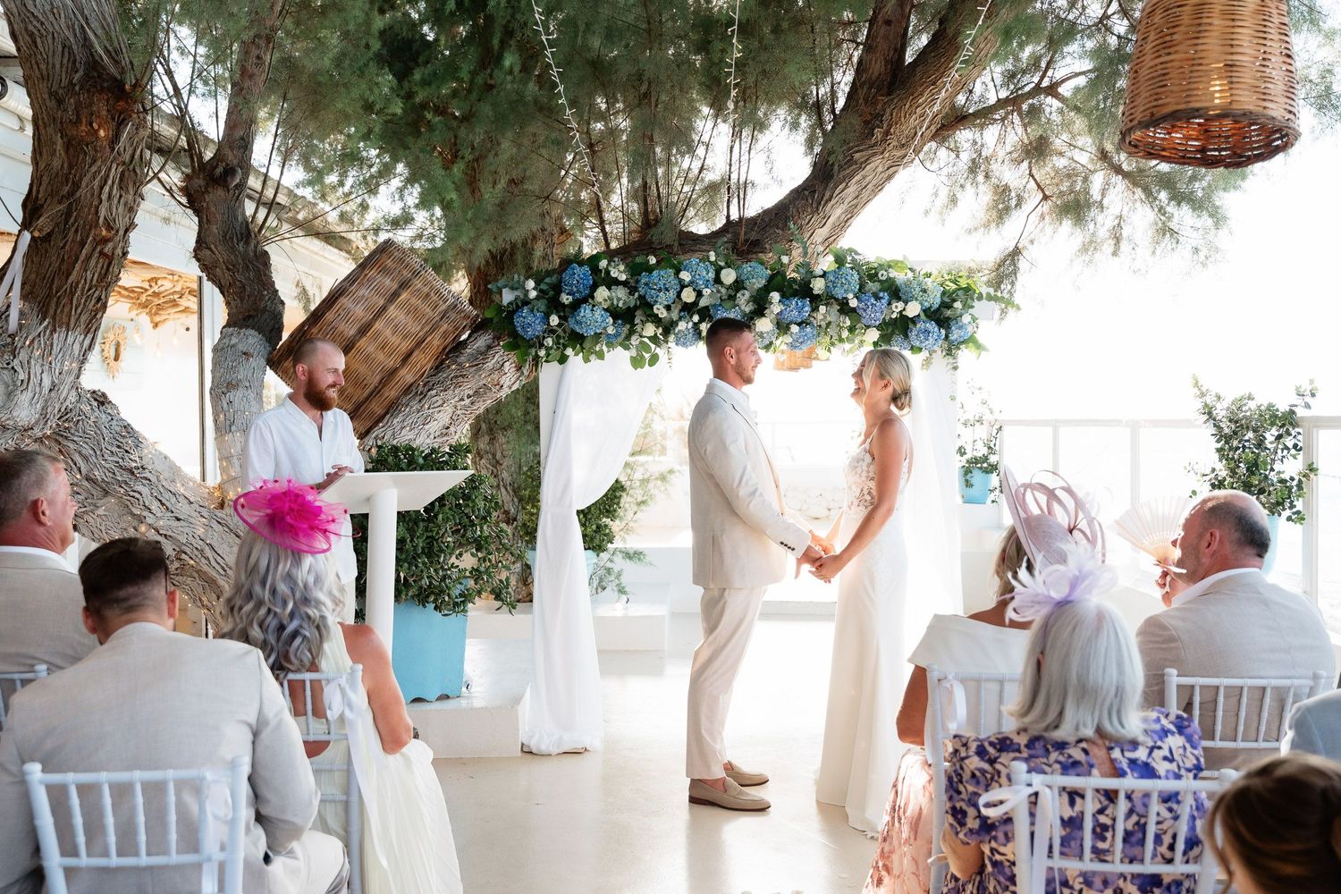 A collage of wedding reception scenes showing white decor, floral arrangements and guests mingling at an outdoor venue.