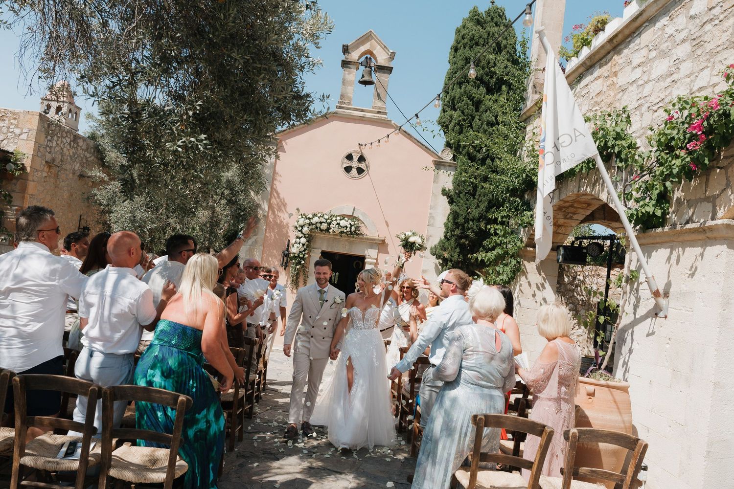Wedding guests mingle and celebrate in a charming outdoor courtyard with stone walls and greenery.