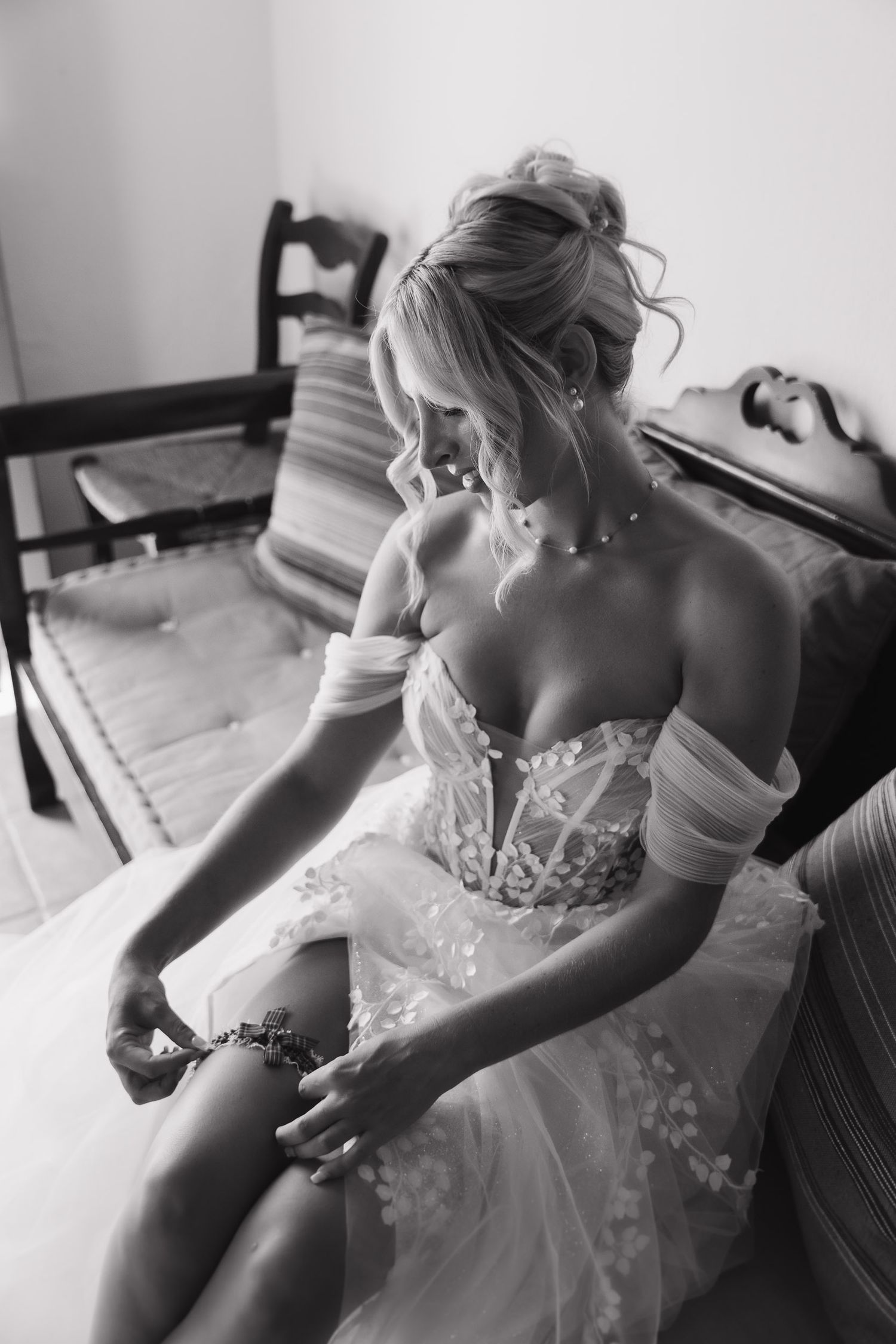 A black and white photo series showing someone adjusting and putting on an elegant lace wedding dress.