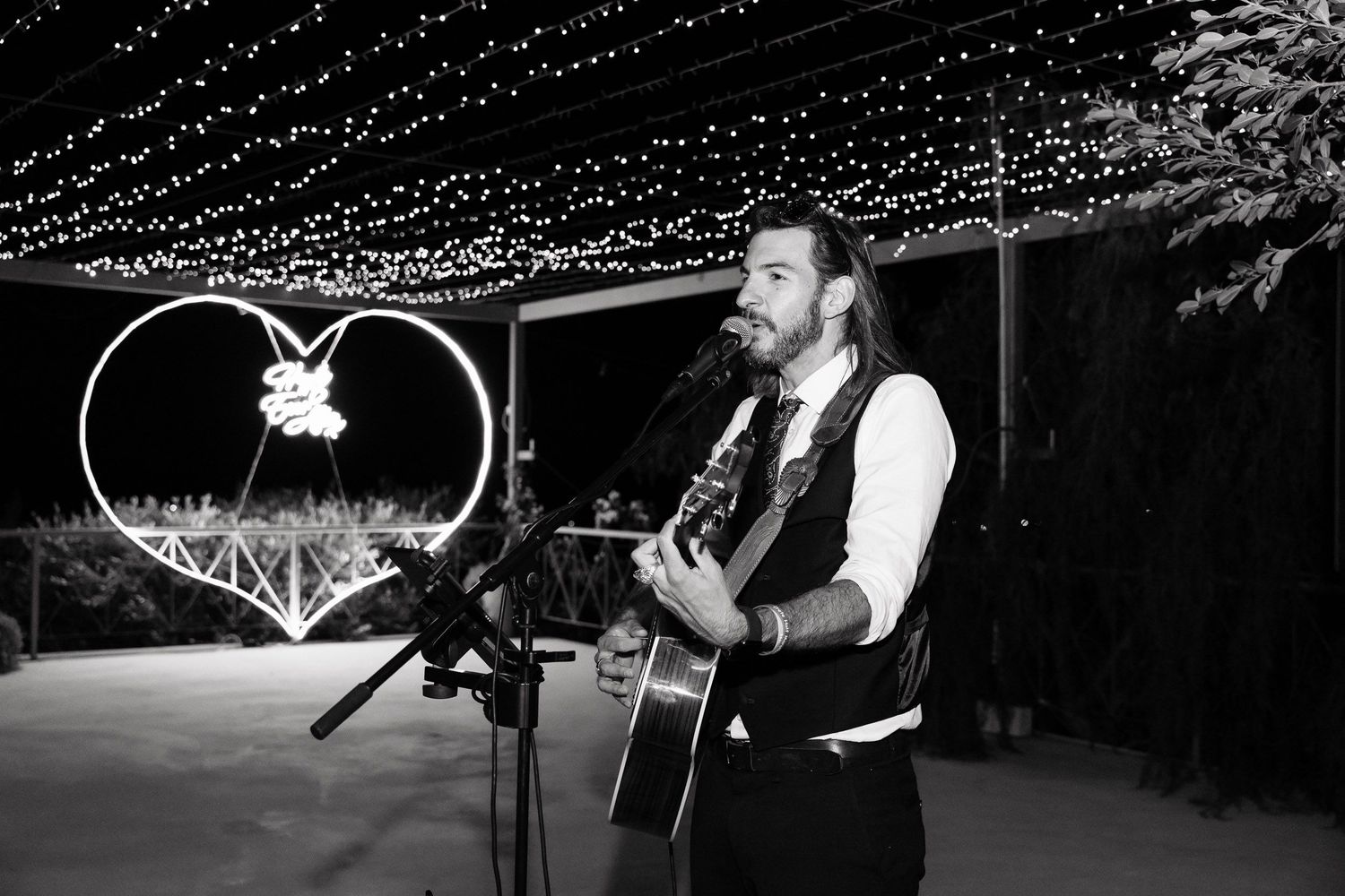A series of black and white photographs showing a performer with an acoustic guitar on stage during a live show.