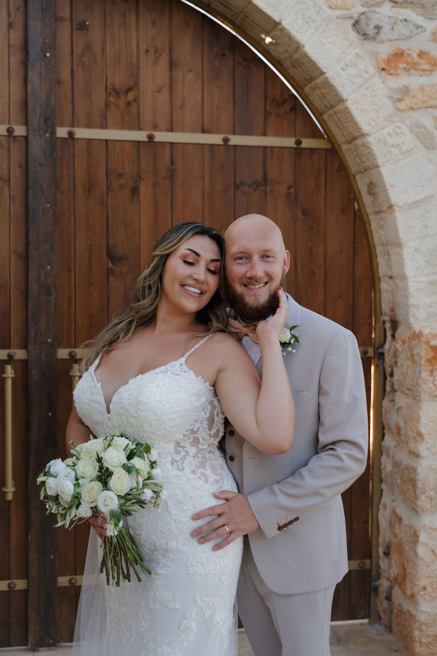 Elegant wedding portrait of couple in front of wooden arched doorway at Ktima Emmeleia, Crete
