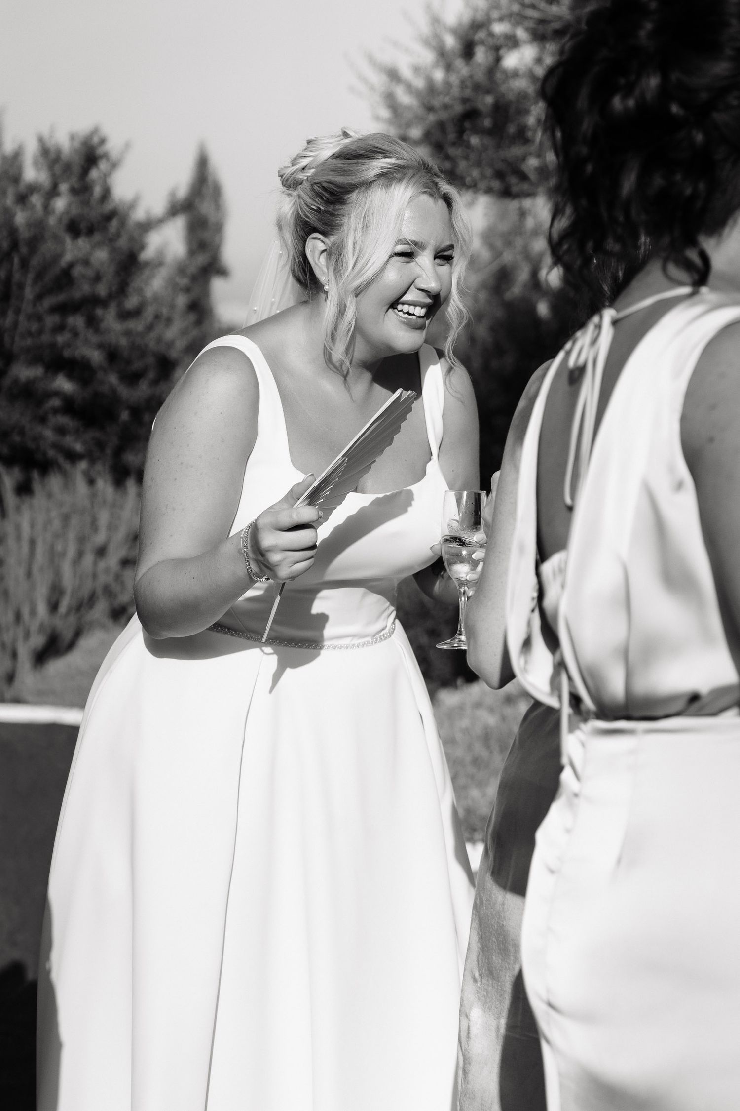 A series of black and white candid photos showing joyful moments and laughter between people in white clothing outdoors.