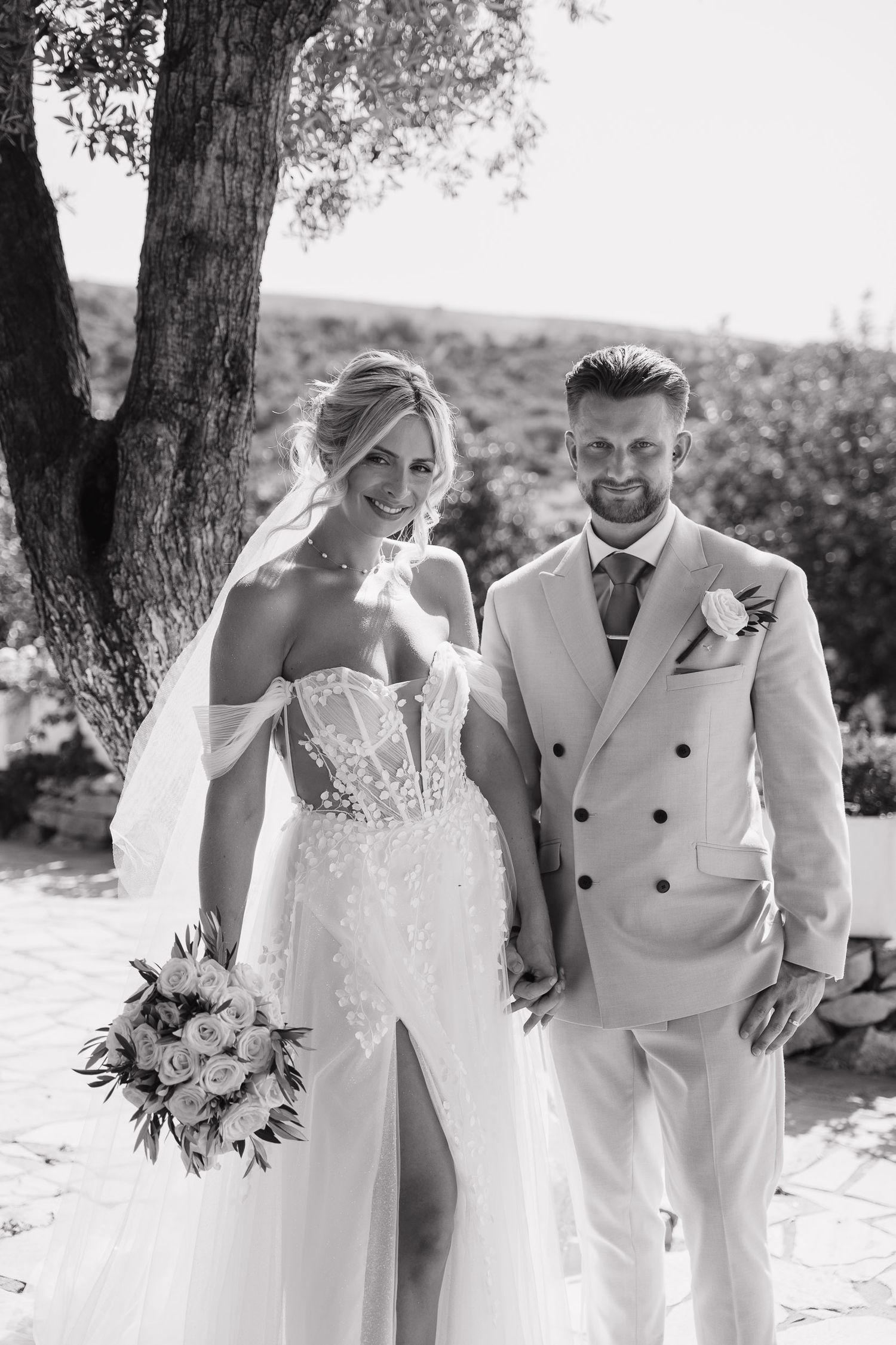 Black and white wedding photos show couple walking together outdoors with bride in lace gown and groom in light suit.
