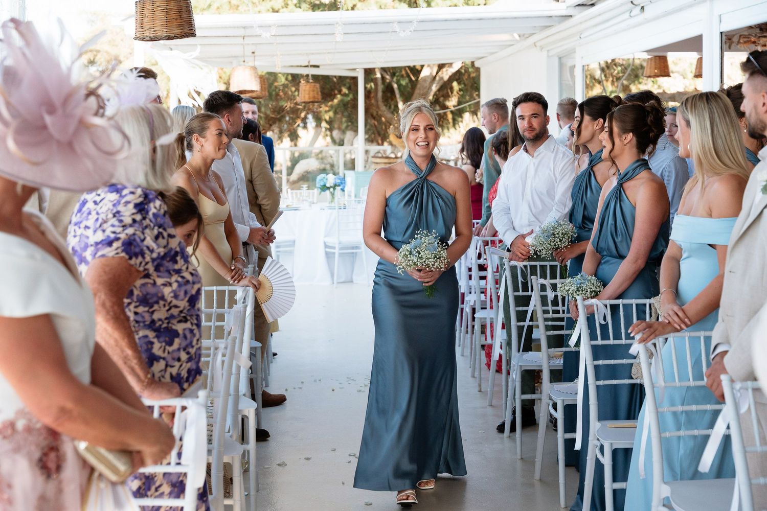 Wedding guests dance and celebrate together at an outdoor reception with white chairs and decorations.