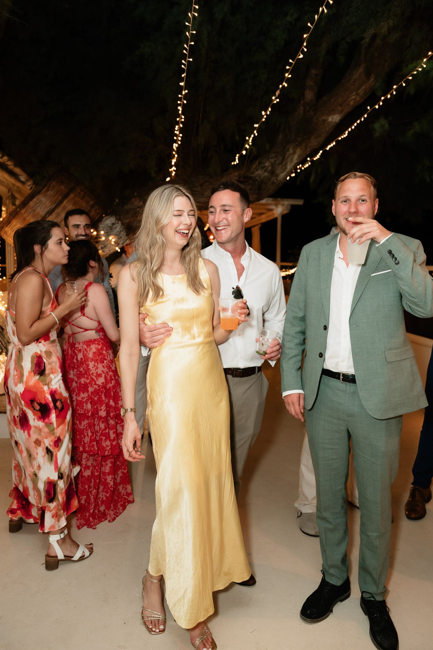 Couples dancing and celebrating at a wedding reception under warm lighting with festive decorations.