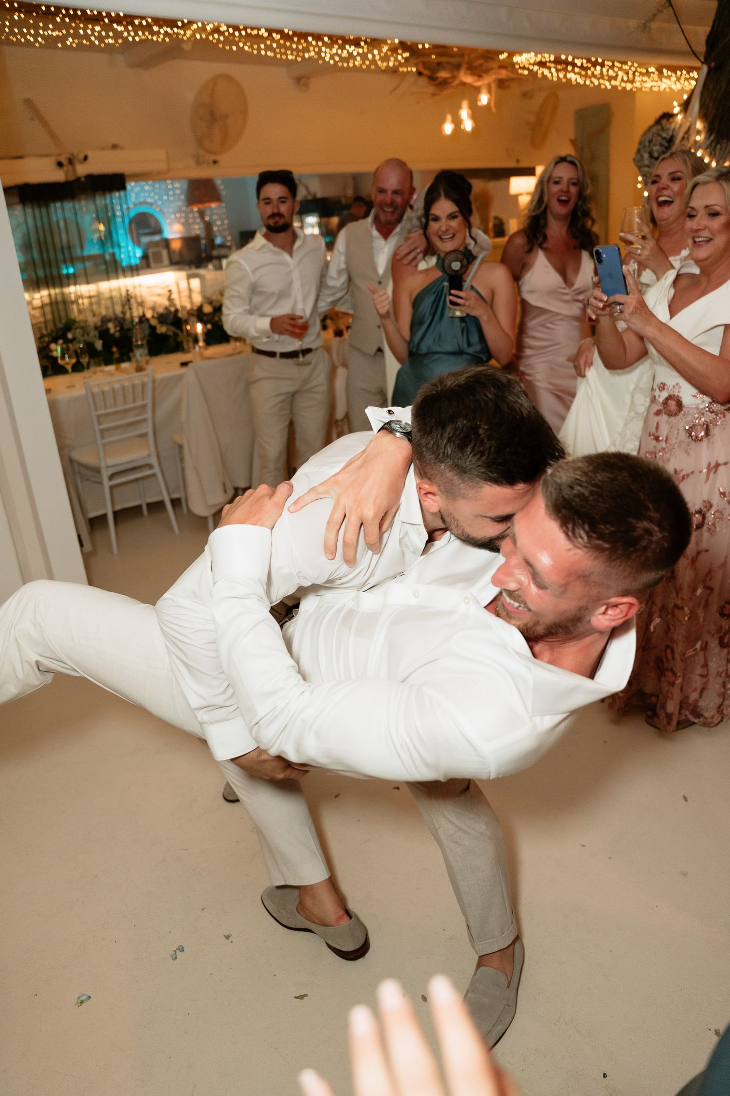 A sequence of photos shows a couple performing a dramatic dance dip in their white attire at a wedding reception.