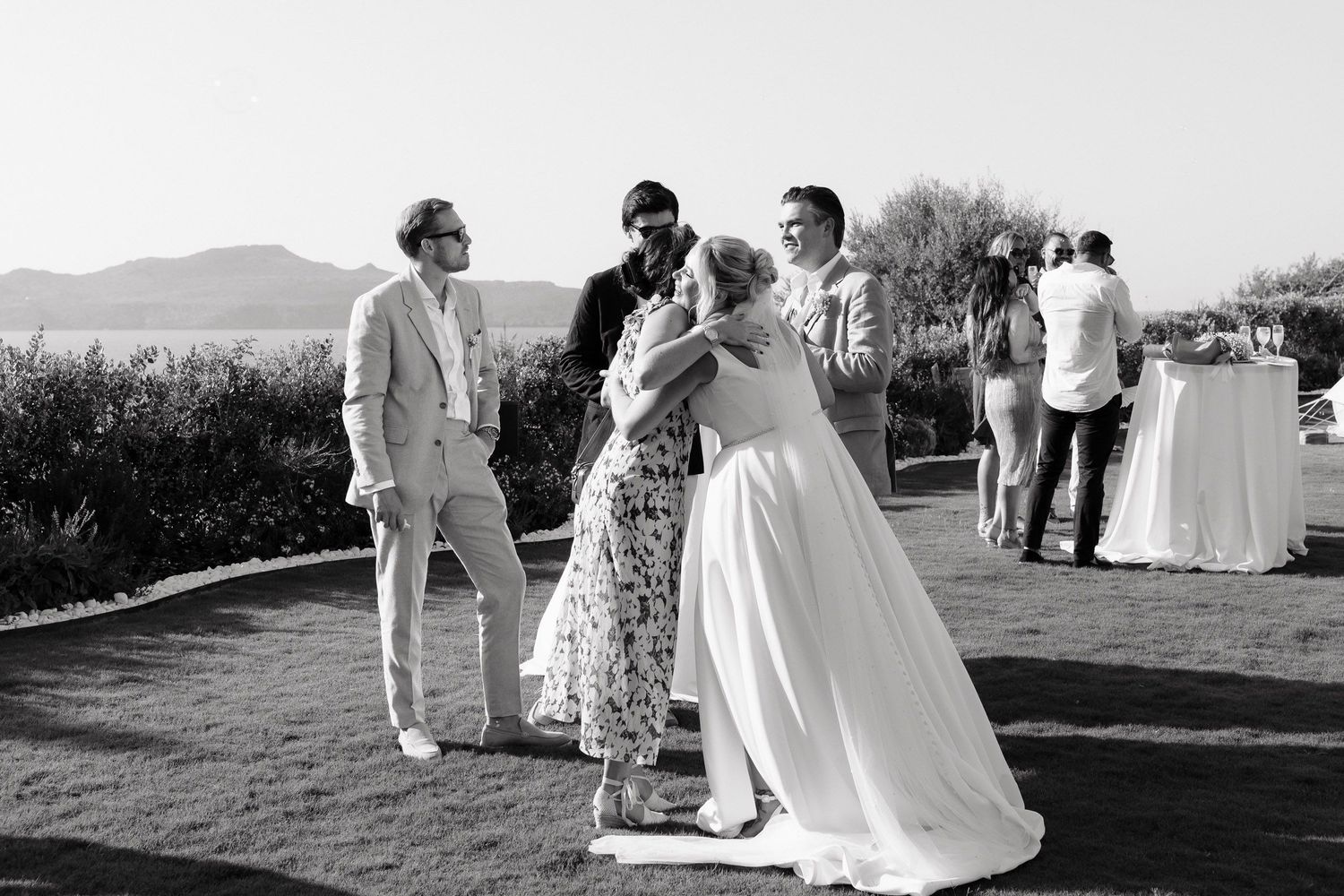A black and white photo montage of an outdoor wedding ceremony with guests gathered on a scenic hilltop.