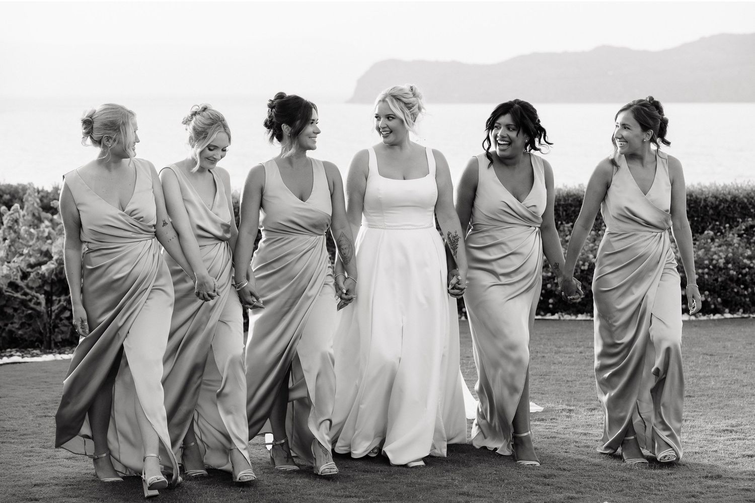 A group of bridesmaids in matching white dresses run playfully across a field in a candid wedding photo sequence.