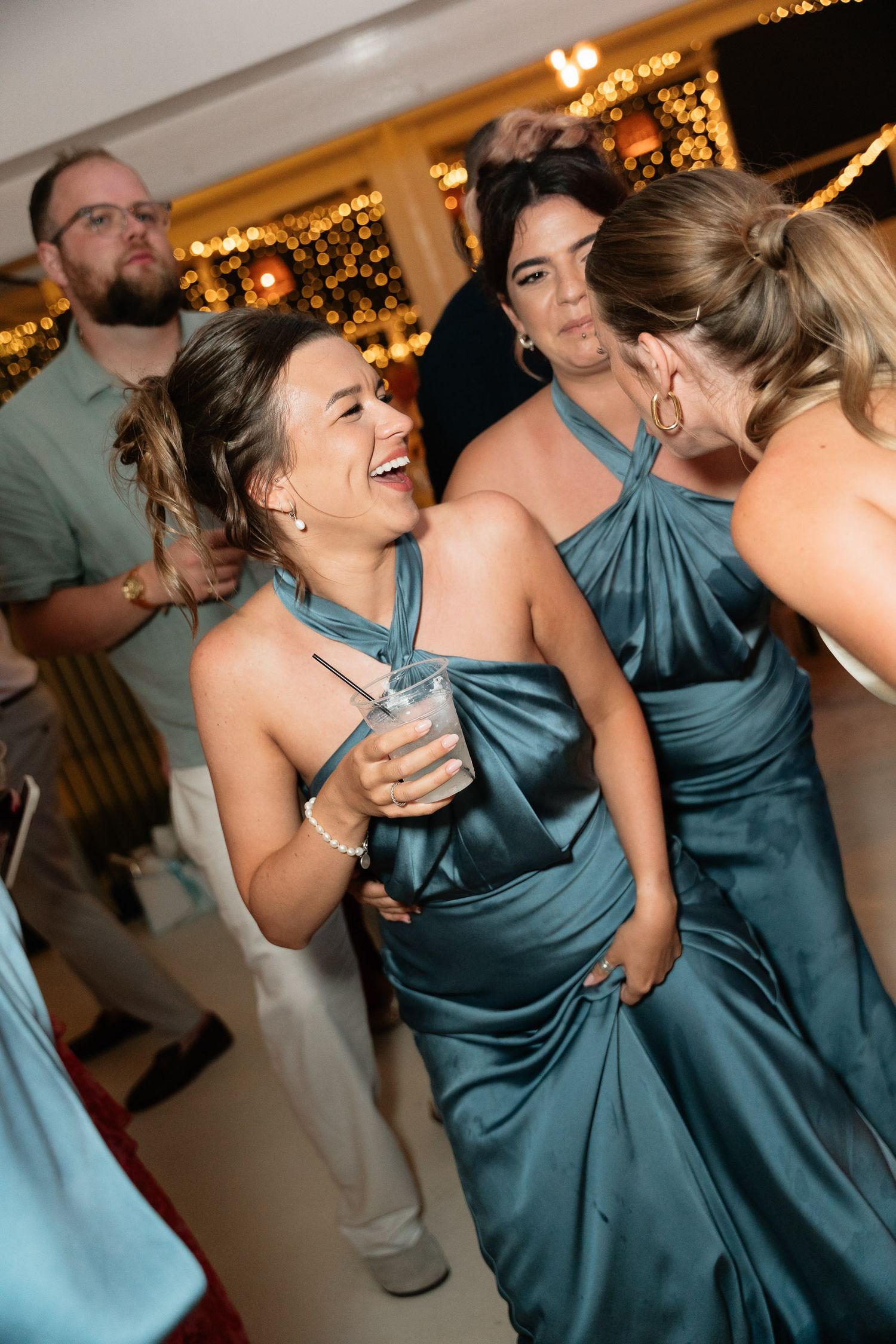 A sequence of photos showing people dancing and laughing at a wedding reception, wearing teal bridesmaid dresses.