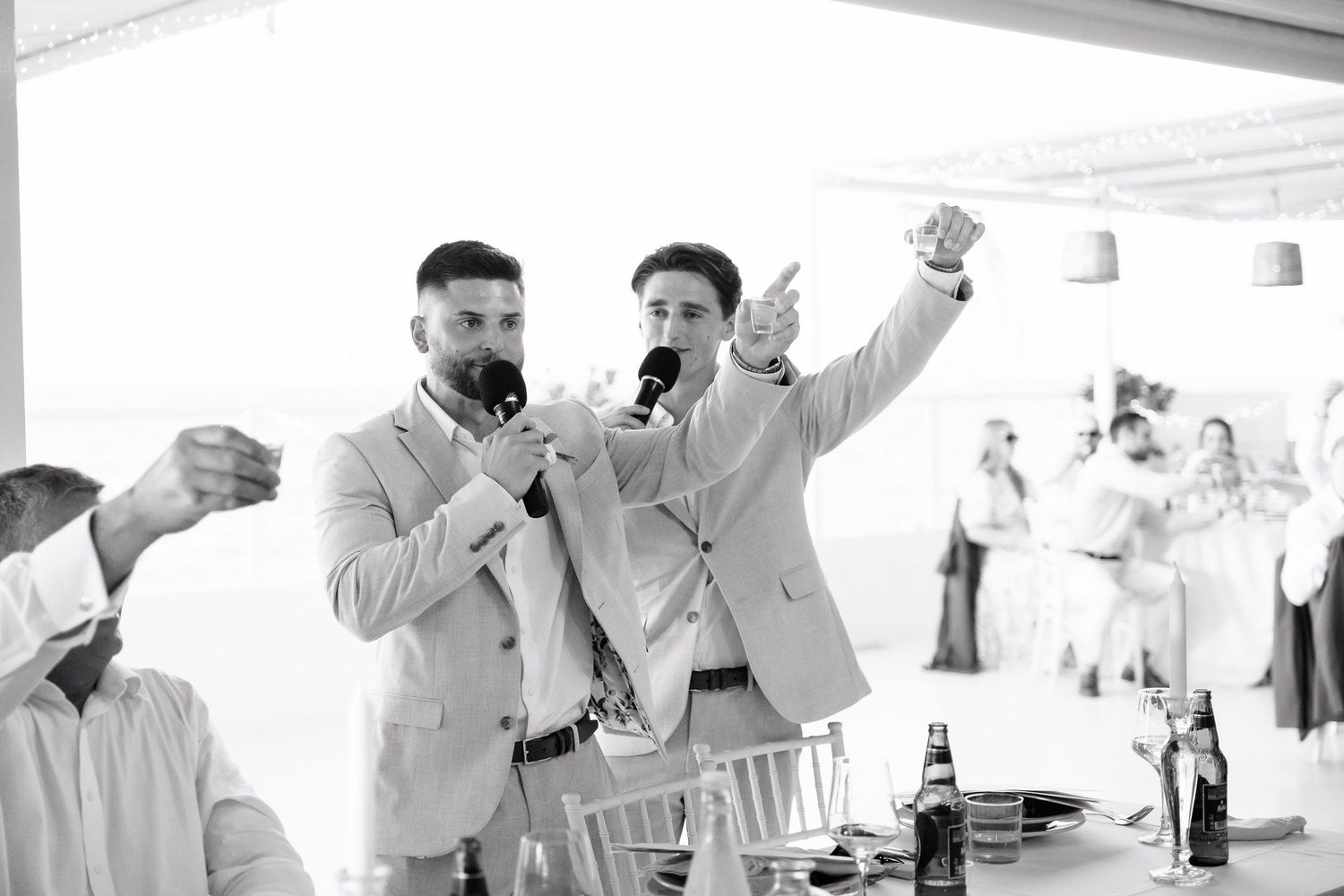 People raising glasses in a toast during a bright indoor celebration.