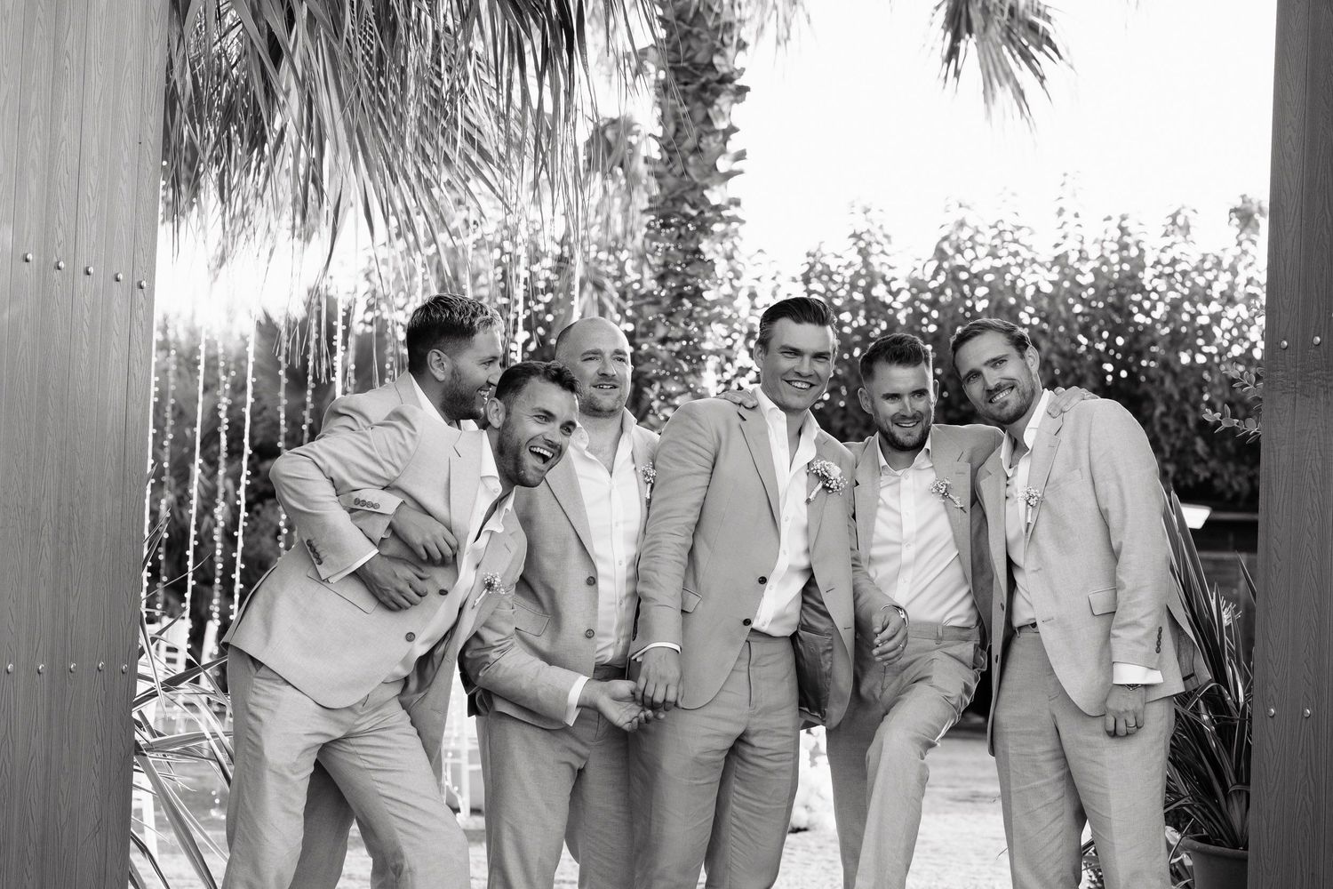 A group of people in formal attire laughing and enjoying themselves at an outdoor event.