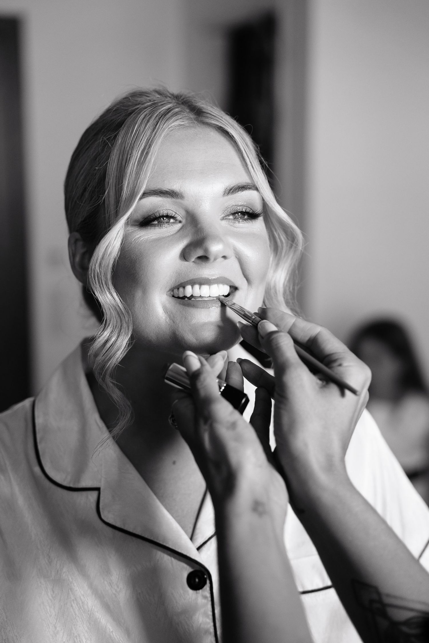 A black and white photo sequence showing the application of makeup with brushes in a professional setting.