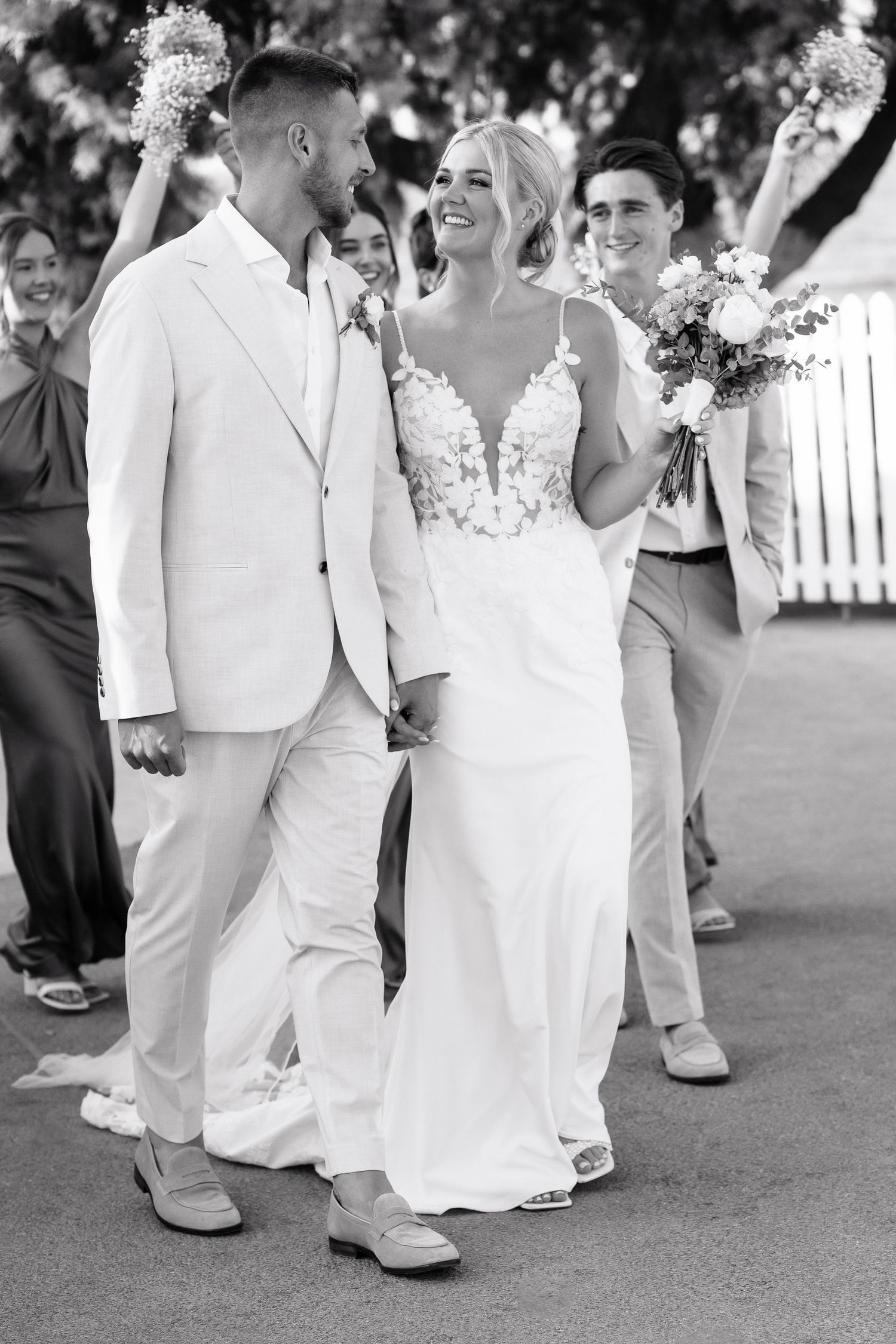 Black and white wedding photo showing a couple sharing a joyful moment together in their elegant white attire.