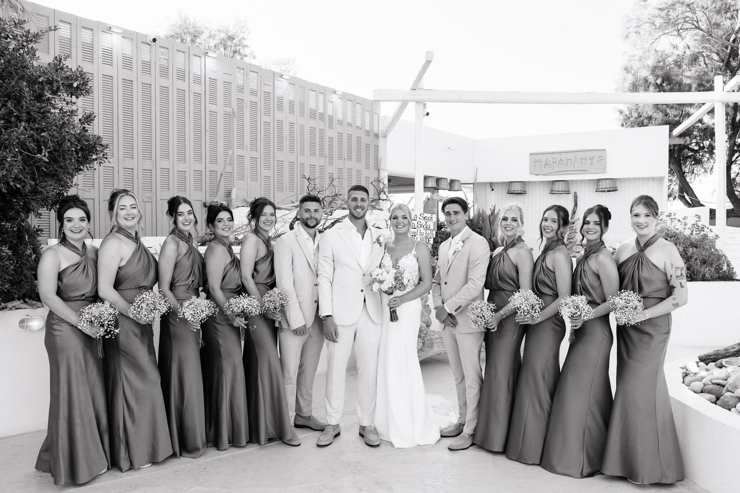 A wedding party poses in a panoramic sequence showing bridesmaids in gray dresses and a bride in white.