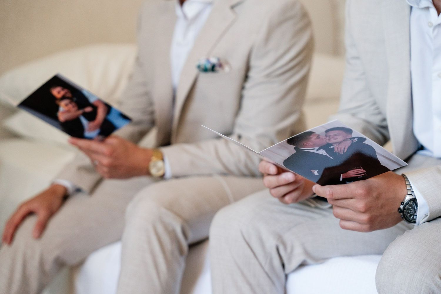 People in light colored suits sit together while looking at their mobile phones during a social gathering.