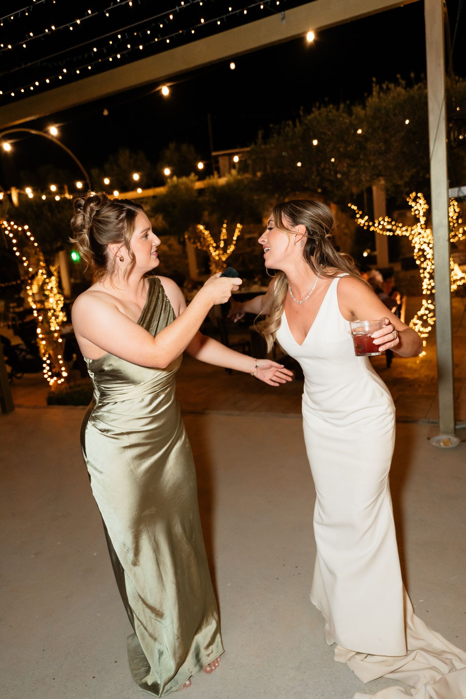 Wedding couple performs a playful dance sequence under twinkling lights at an outdoor reception.