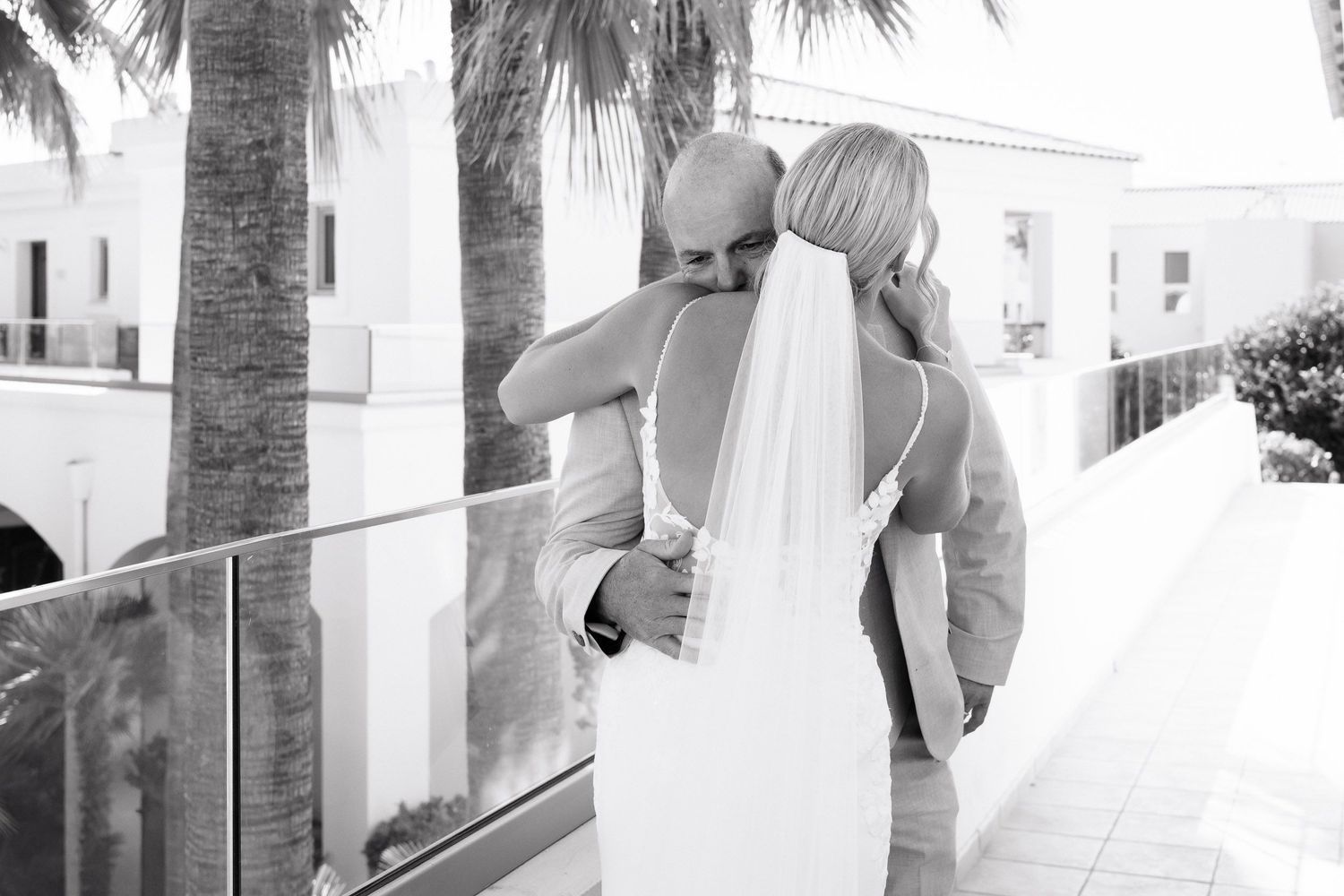 A series of five black and white photos showing a couple walking through a tropical resort setting with palm trees.