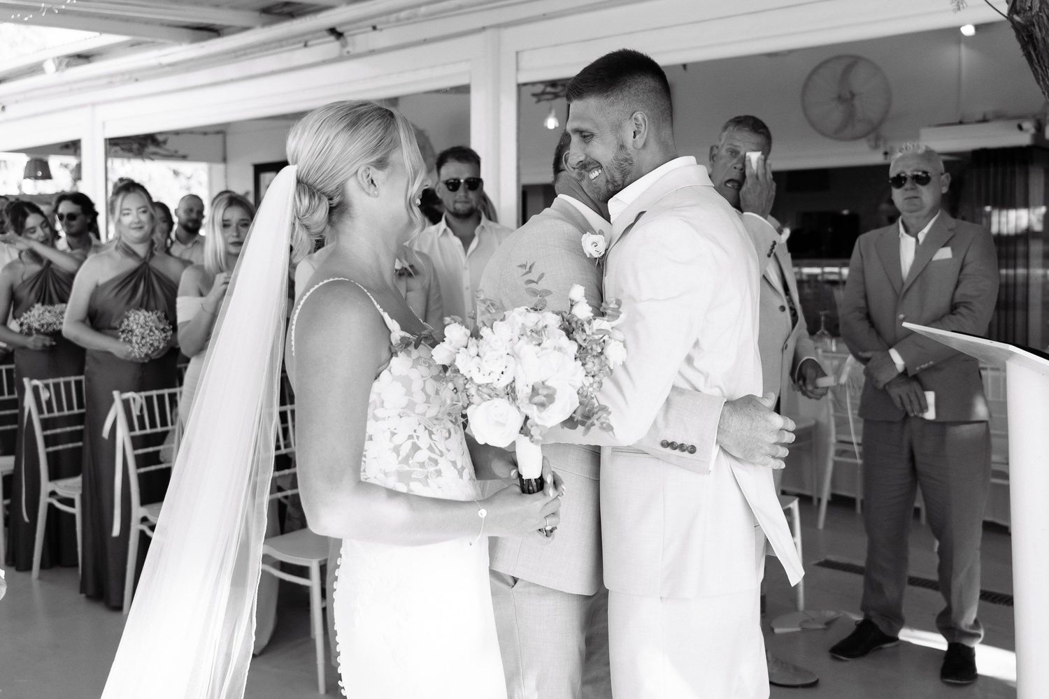 Black and white wedding reception photos showing guests dancing, mingling and celebrating at an indoor venue.