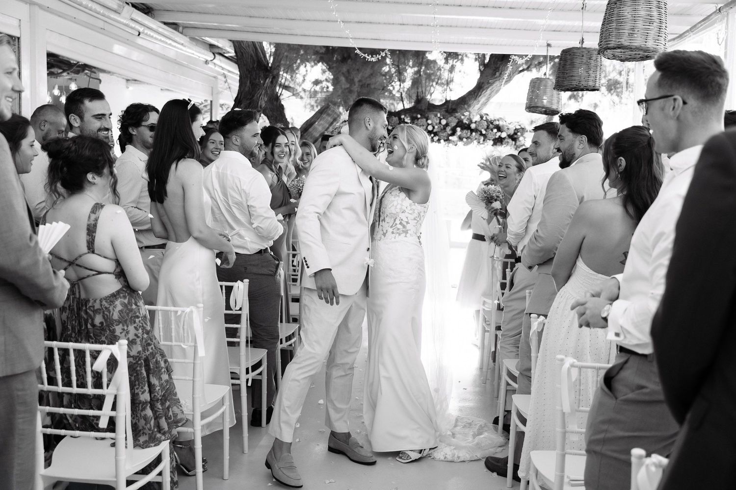 A black and white panoramic photograph shows guests mingling at an elegant outdoor reception event.