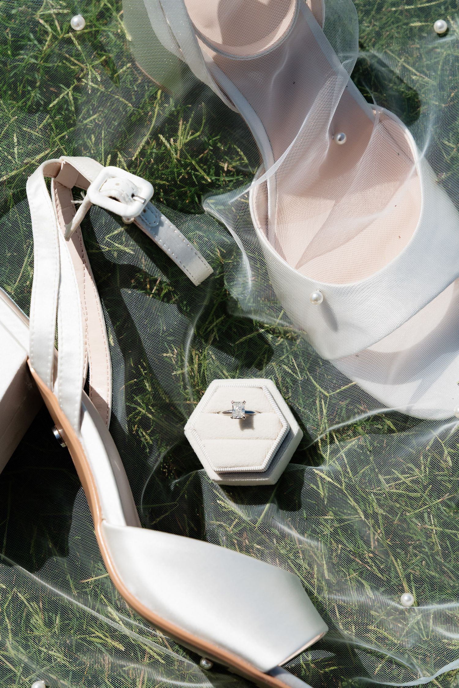 White leather ballet flats with buckle straps displayed on grass in multiple angles.