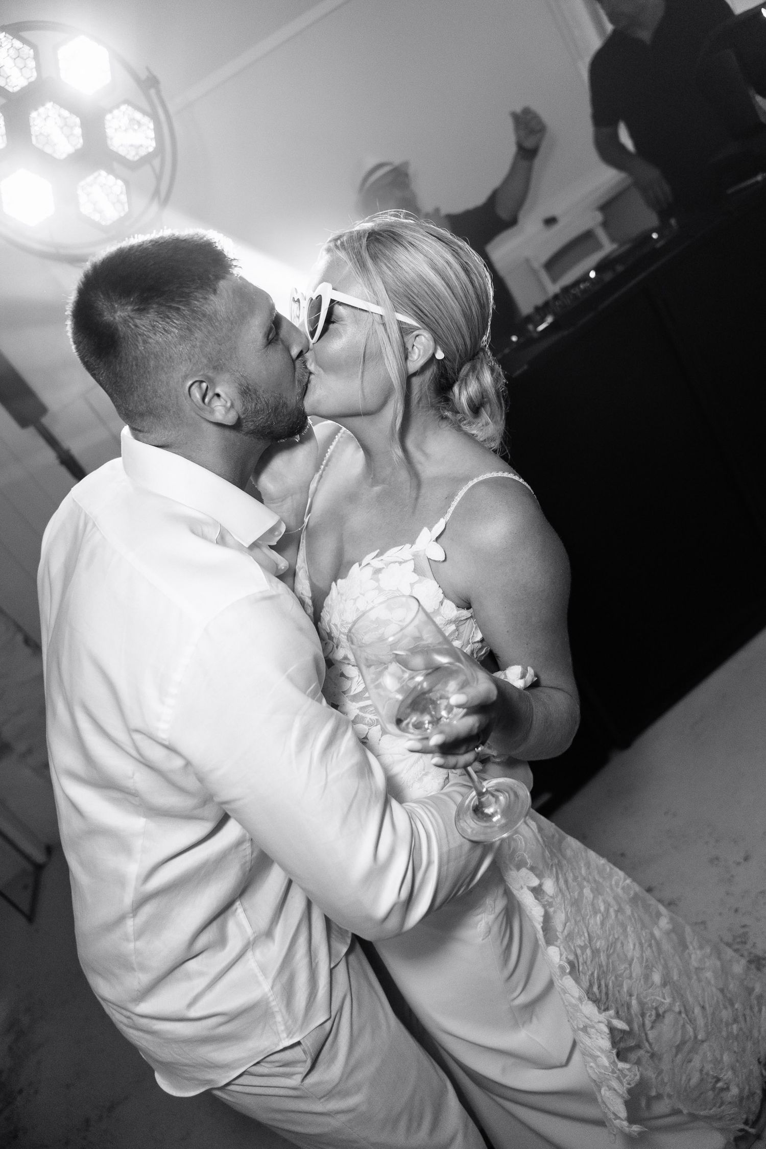 A romantic black and white photo series showing a couple sharing tender kisses at their wedding celebration.