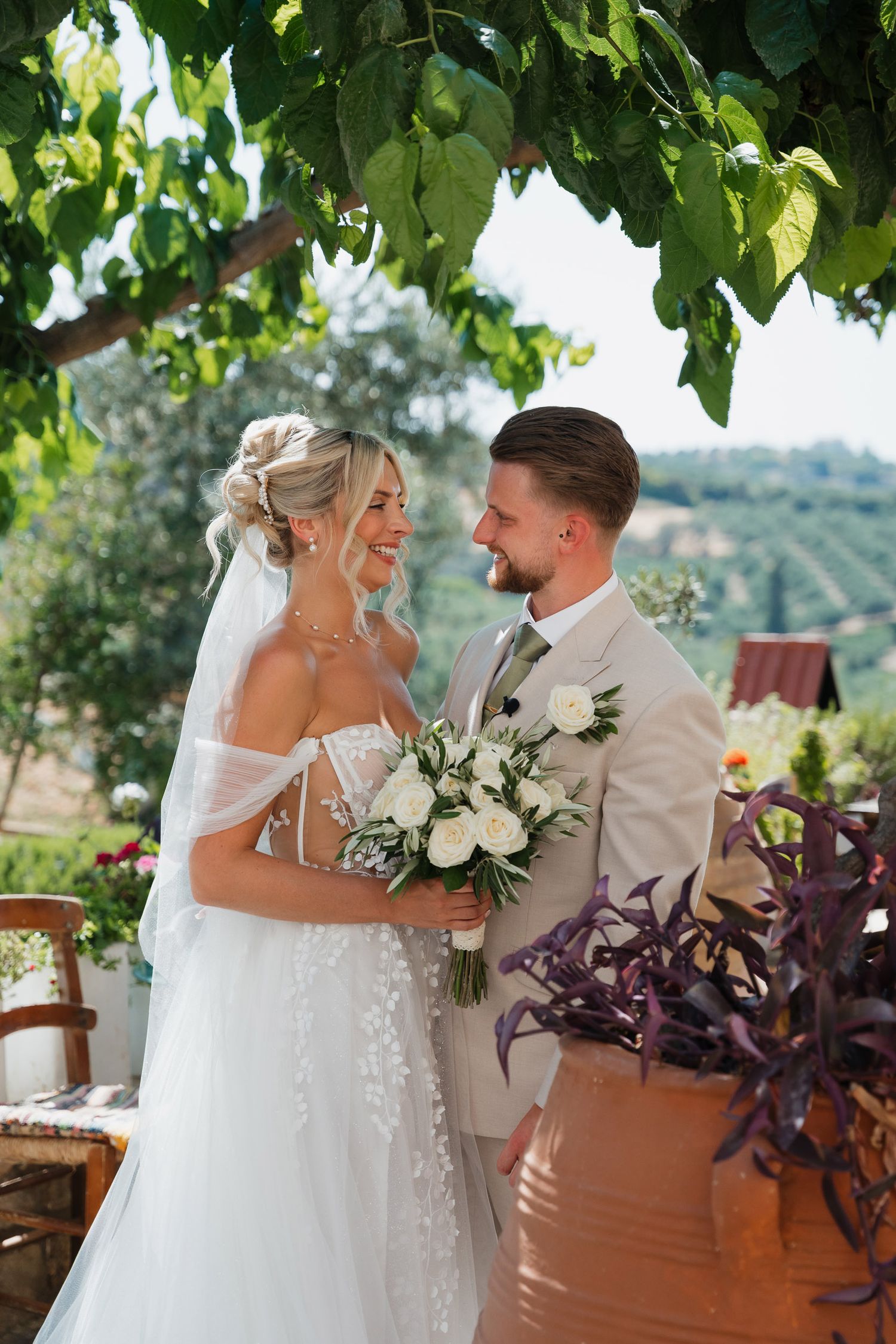 A couple shares a joyful moment together during their outdoor wedding ceremony surrounded by lush greenery.